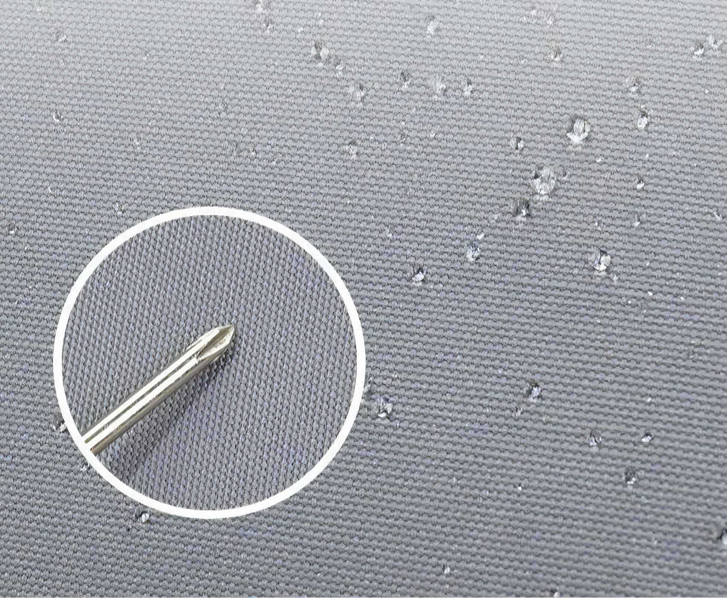 Nahaufnahme eines grauen Stoffes mit Wassertropfen und einem Schraubendreherkopf in einem weißen Kreis.