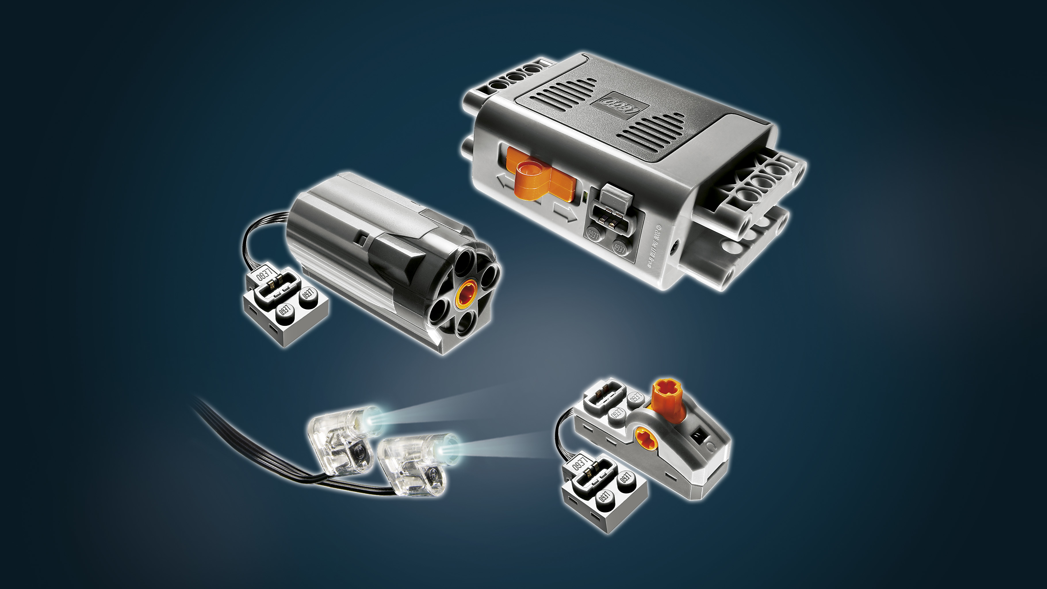 Elementy LEGO Technic: silniki, światła i jednostki sterujące w kolorze szarym i czarnym. Niektóre części mają pomarańczowe i przezroczyste elementy.