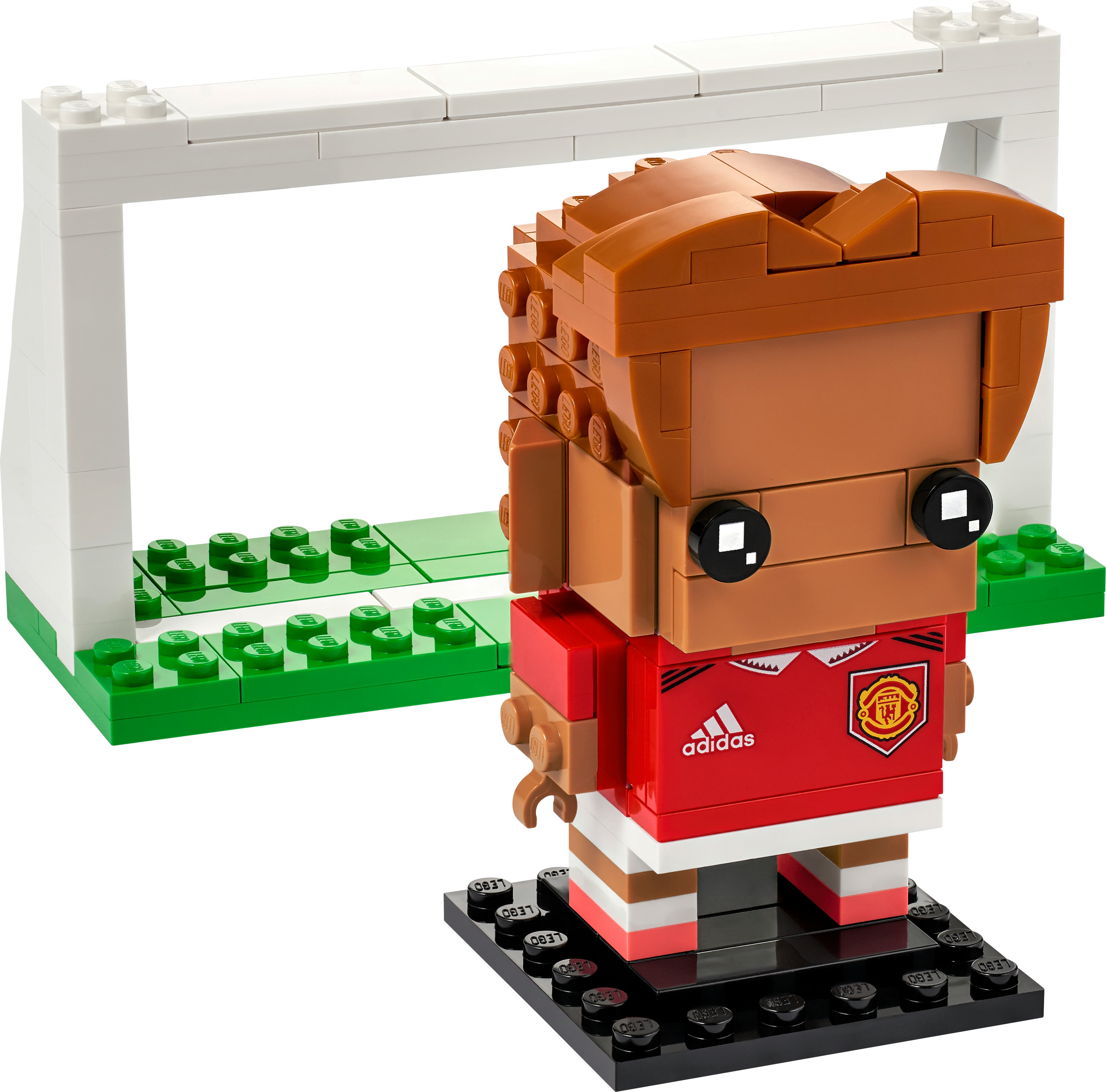 Kırmızı üniforma, kahverengi saçlı bir futbolcu Lego figürü ve arka planda beyaz bir kale.