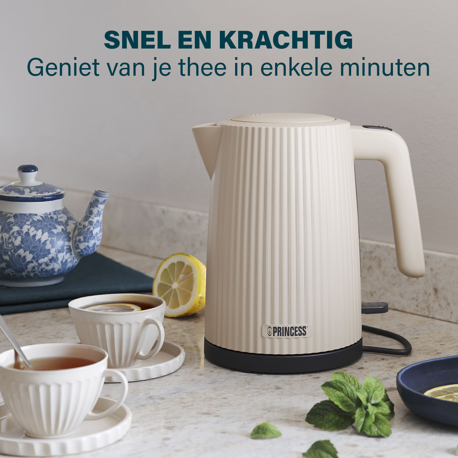 Beżowy czajnik elektryczny, filiżanki herbaty z cytryną, czajniczek i listki mięty na blacie. Tekst: 'Szybko i wydajnie'.