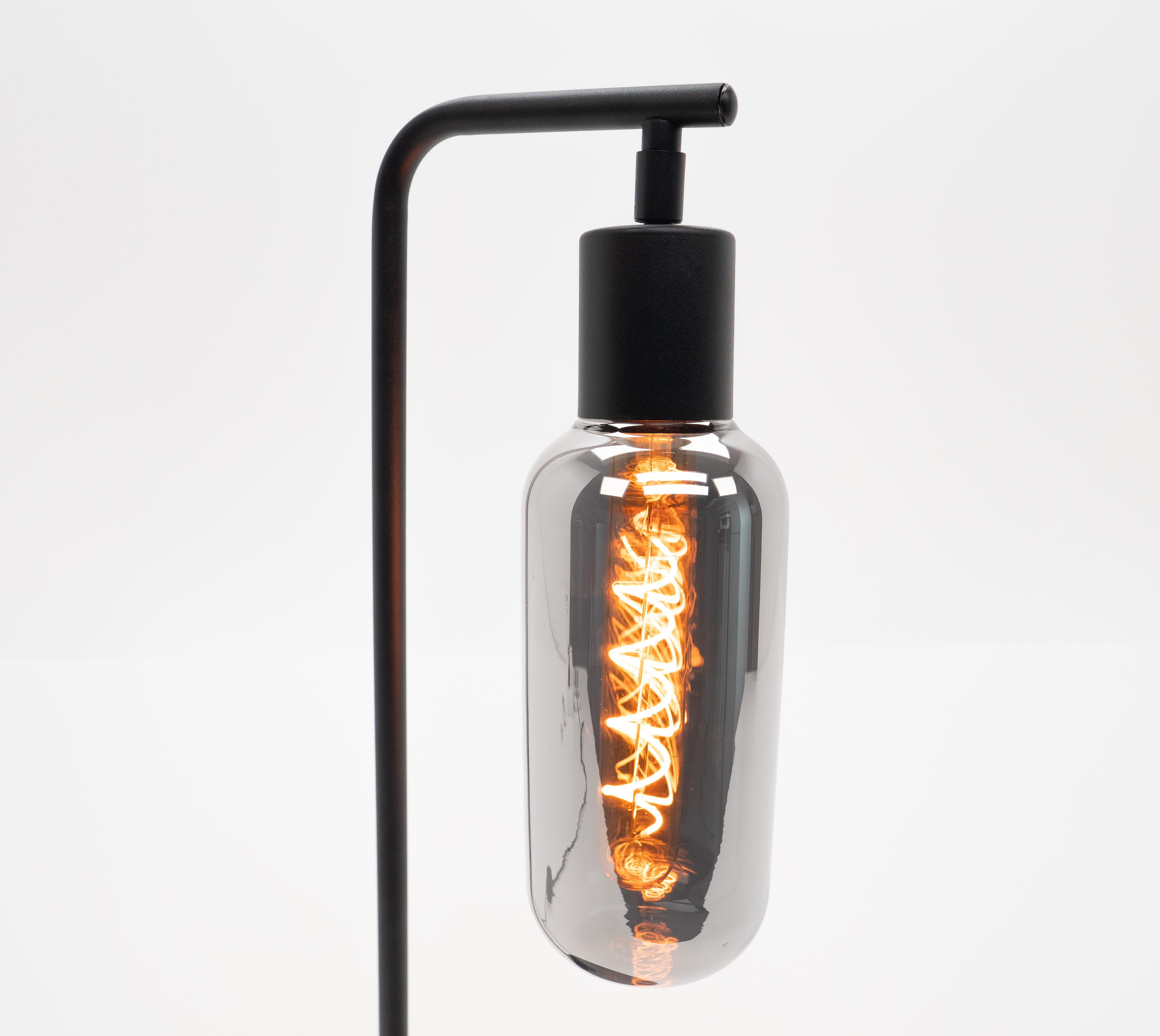 Una lampada nera con una lampadina trasparente, grigia, contenente un filamento luminoso, arancione e illuminato.