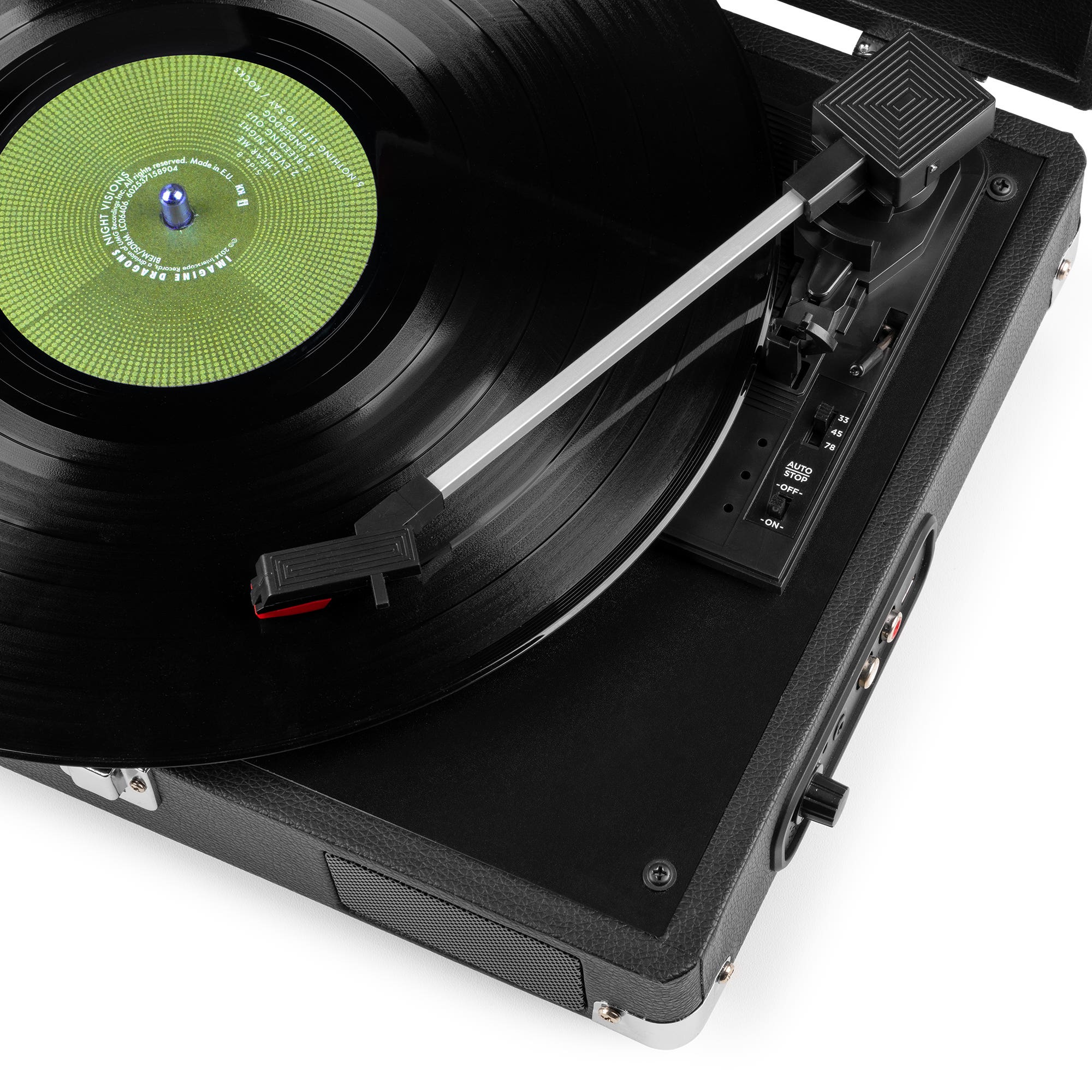 A black record on a black turntable. The record player is on a white surface. The record has a green label.