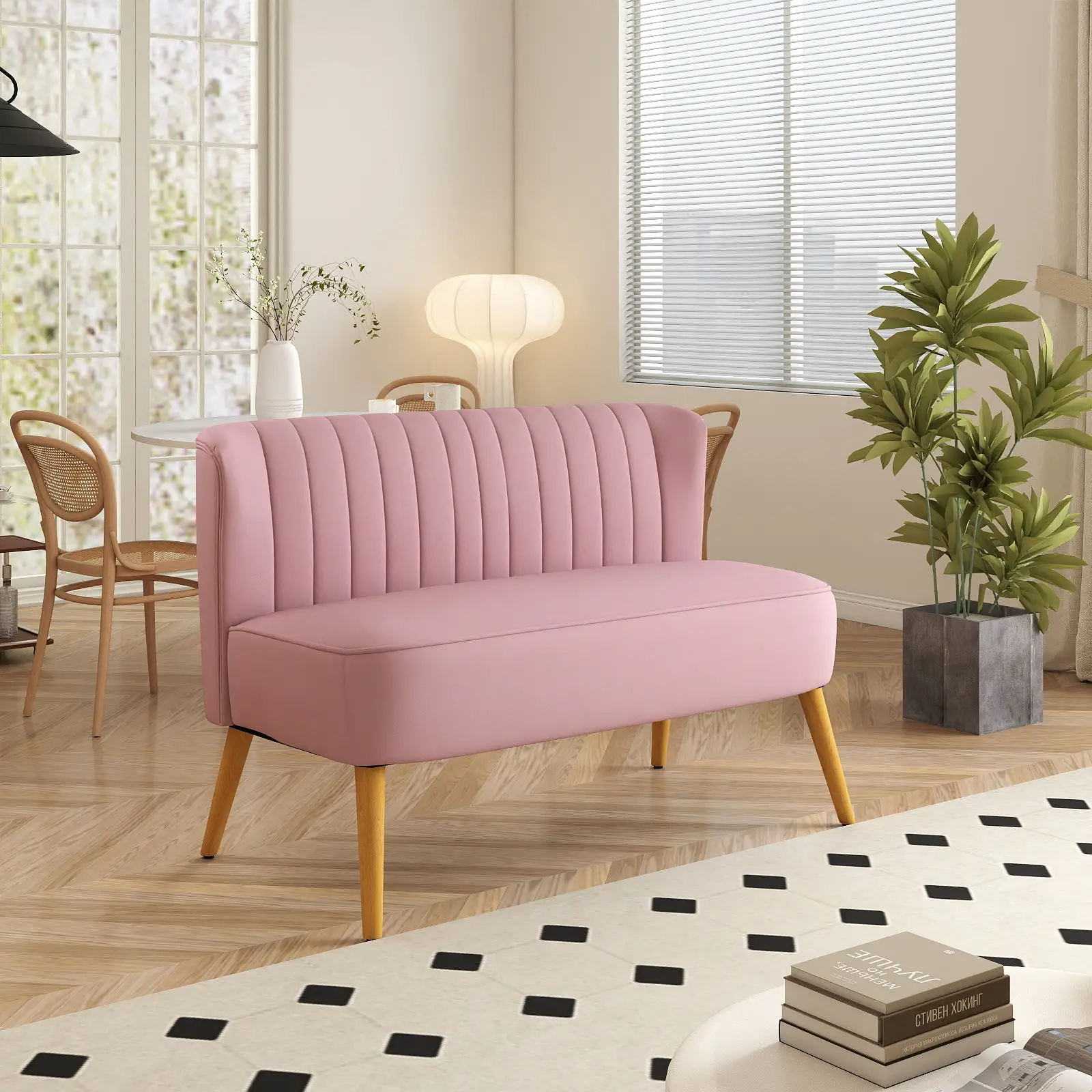 Ein rosa Sofa mit Holzbeinen steht in einem Wohnzimmer. Rechts vom Sofa steht eine Pflanze im Topf.