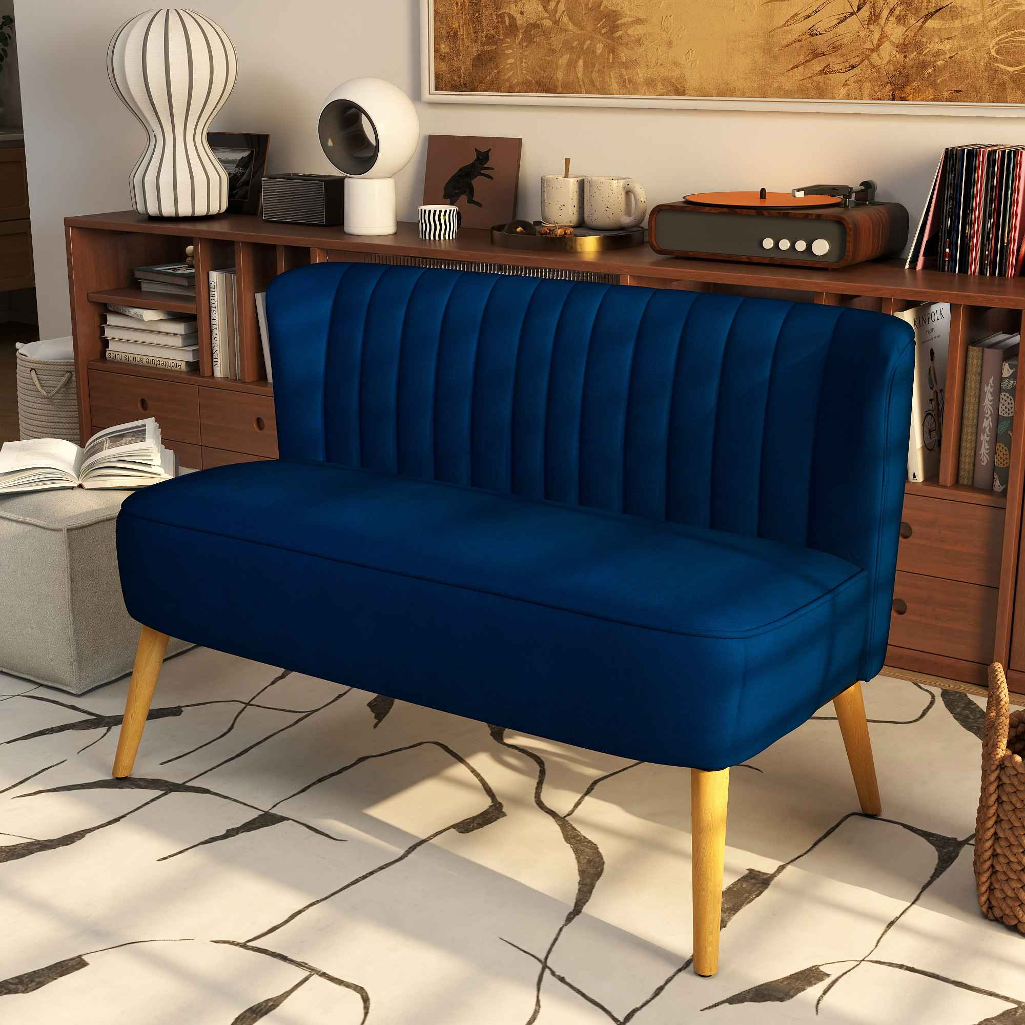 Ein blaues Samtsofa mit Holzbeinen steht in einem Raum. Ein Holzschrank und Dekoration sind im Hintergrund.