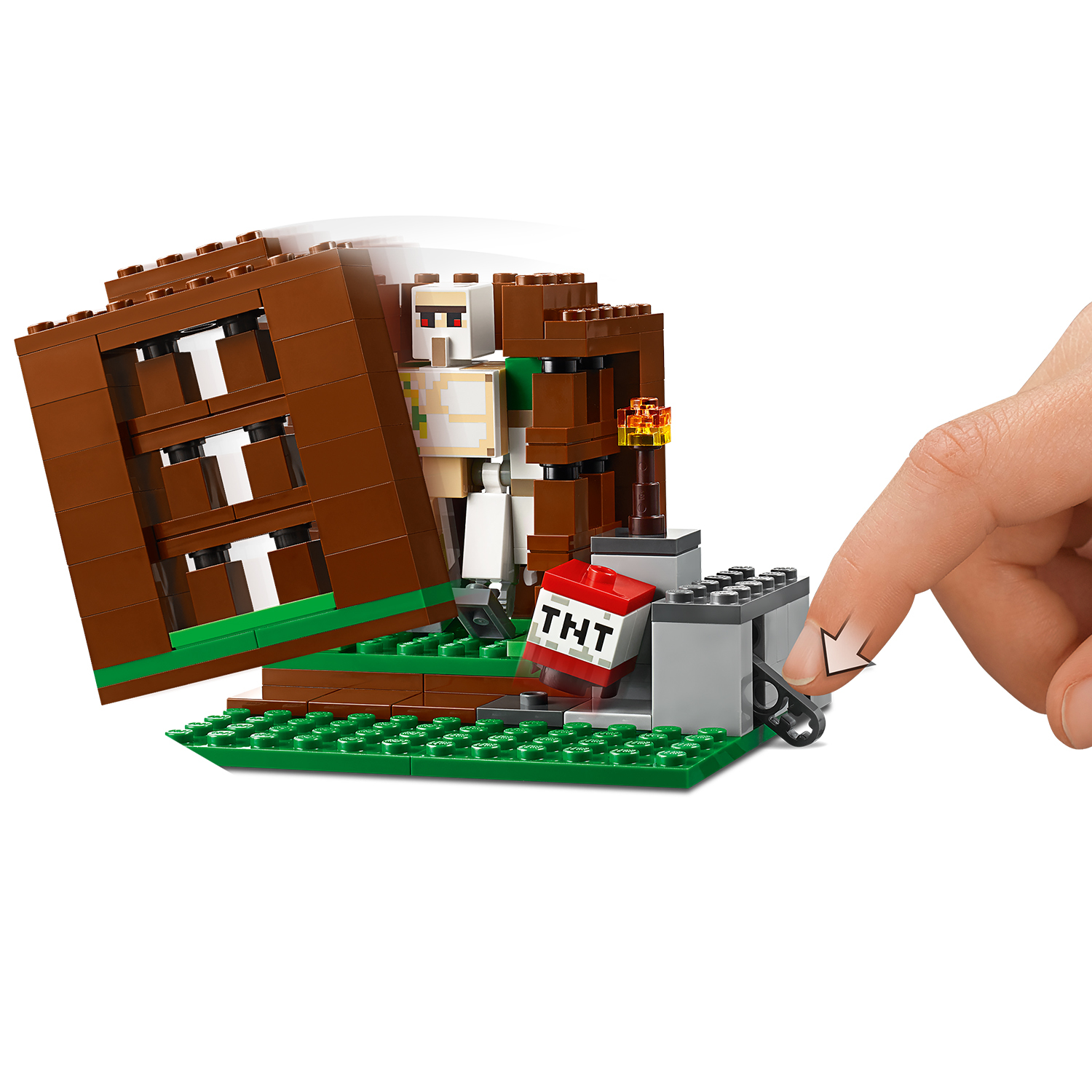 Scena Lego Minecraft z brązową strukturą, TNT, postacią i ręką uruchamiającą akcję, na zielonej podstawie.