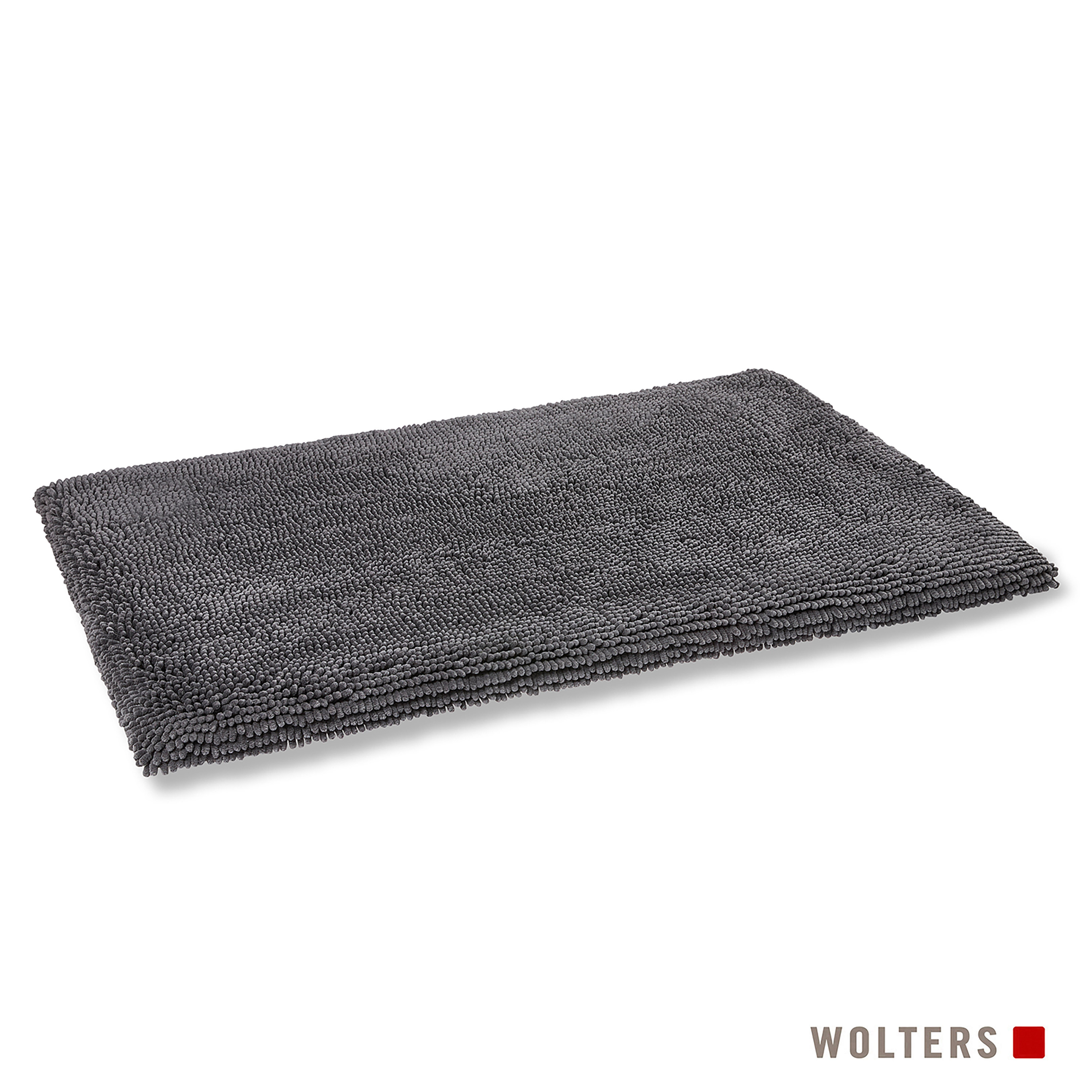 Eine rechteckige, dunkelgraue Badematte liegt auf einer weißen Oberfläche. Die Matte hat eine strukturierte, saugfähige Oberfläche. Die Marke 'Wolters' ist unten.