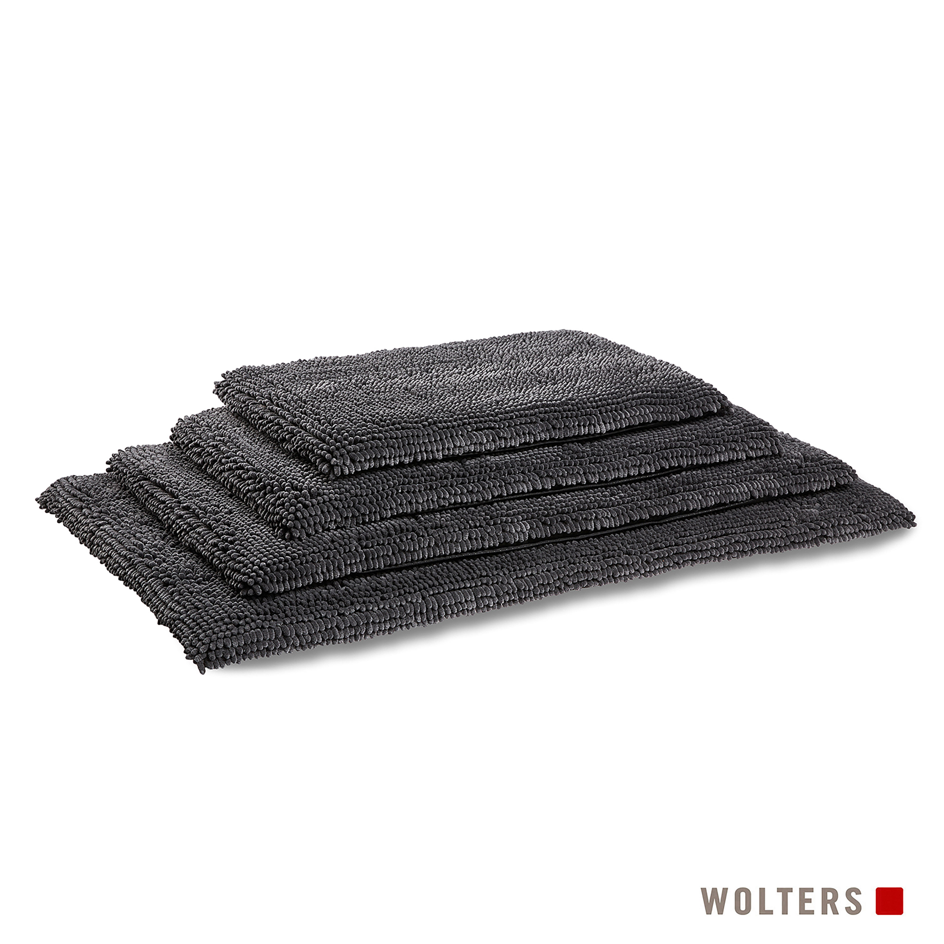 Drei graue Badematten sind gestapelt. Die Matten haben eine strukturierte Oberfläche. Wolters-Logo unten rechts.