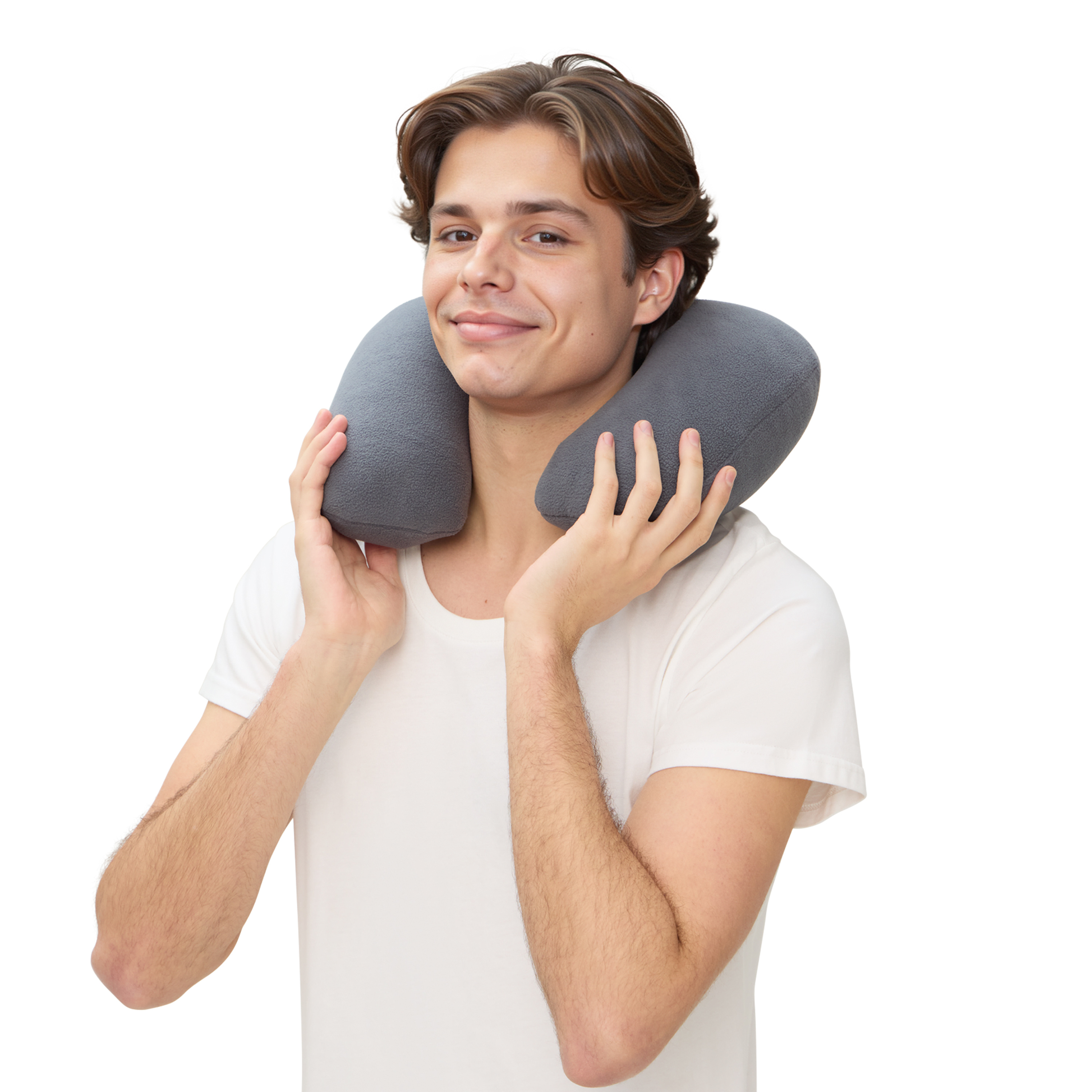 Un joven sostiene una almohada gris para el cuello, sonriendo. Viste una camiseta blanca sobre fondo blanco.