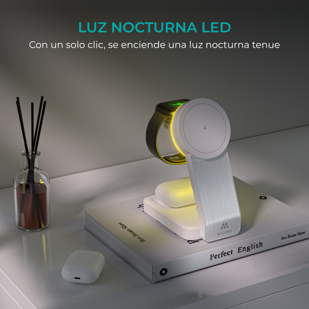 Biała i srebrna stacja ładująca ze smartwatchem, słuchawkami AirPods i książką, oświetlona miękką, żółtą poświatą.