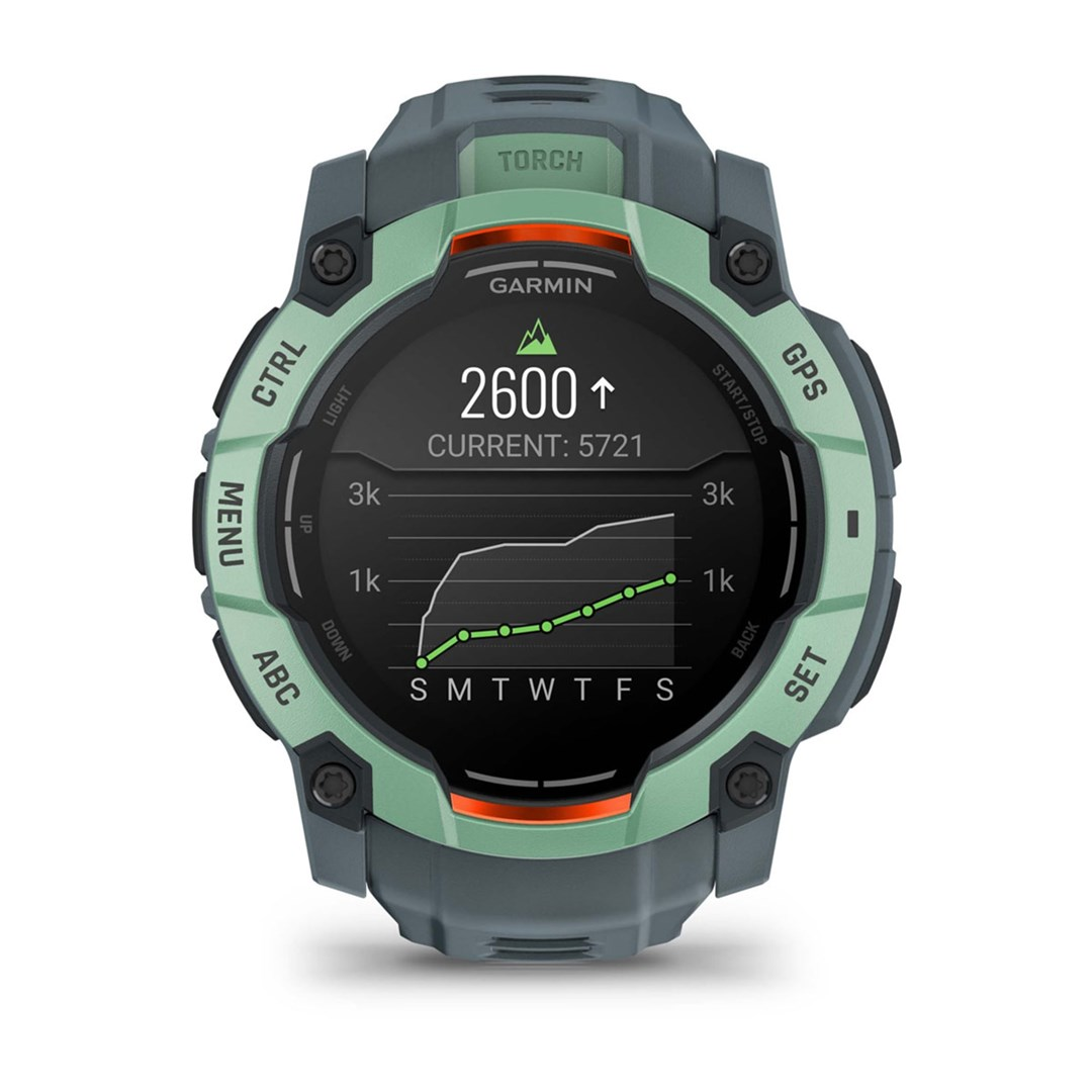 Zegarek Garmin z zieloną i szarą obudową wyświetla kroki, wykres i inne dane. Ekran pokazuje 2600 kroków i aktualnie 5721.
