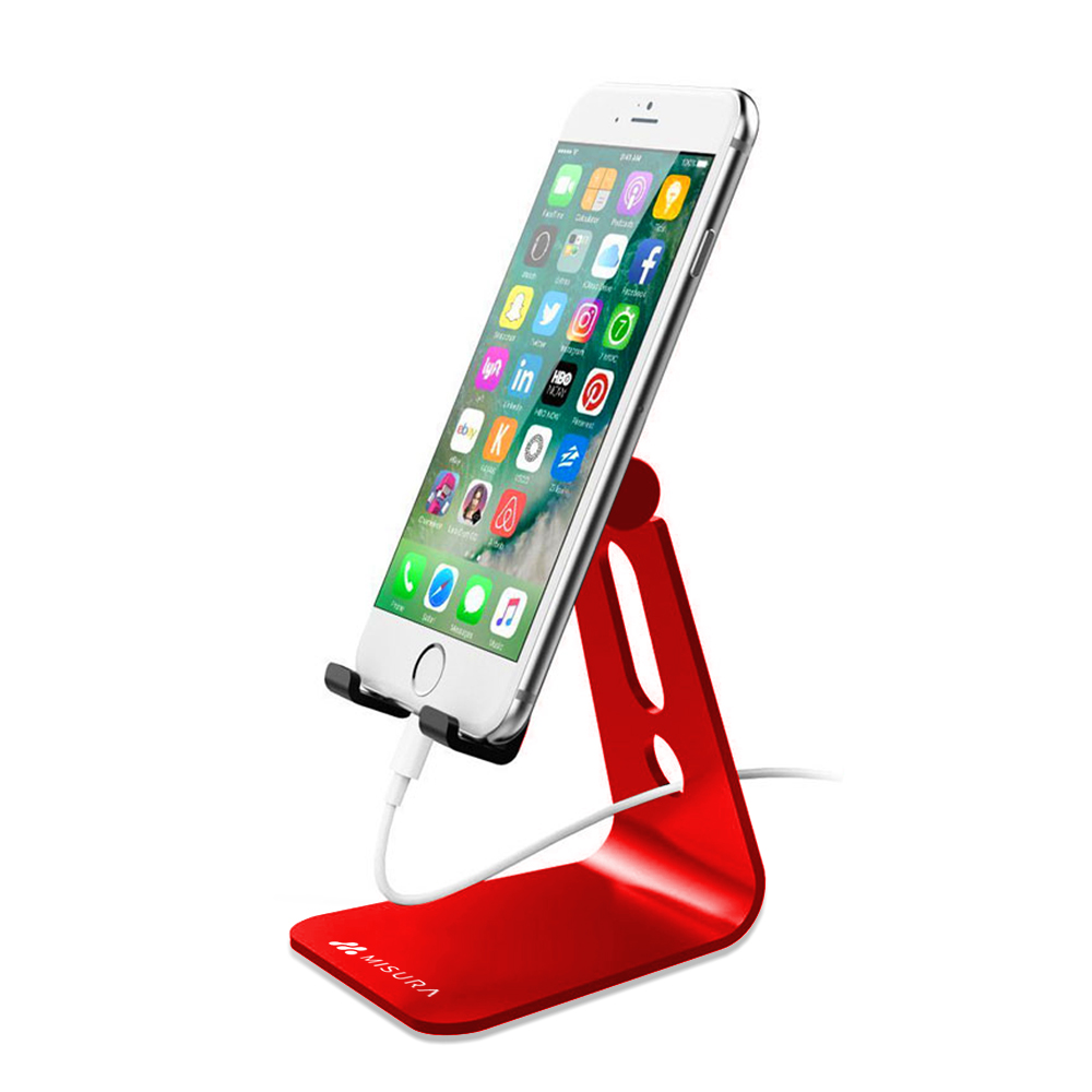 Uno smartphone bianco mostra app ed è su un supporto rosso. Un cavo di ricarica bianco è collegato. Il supporto ha il logo Misura.