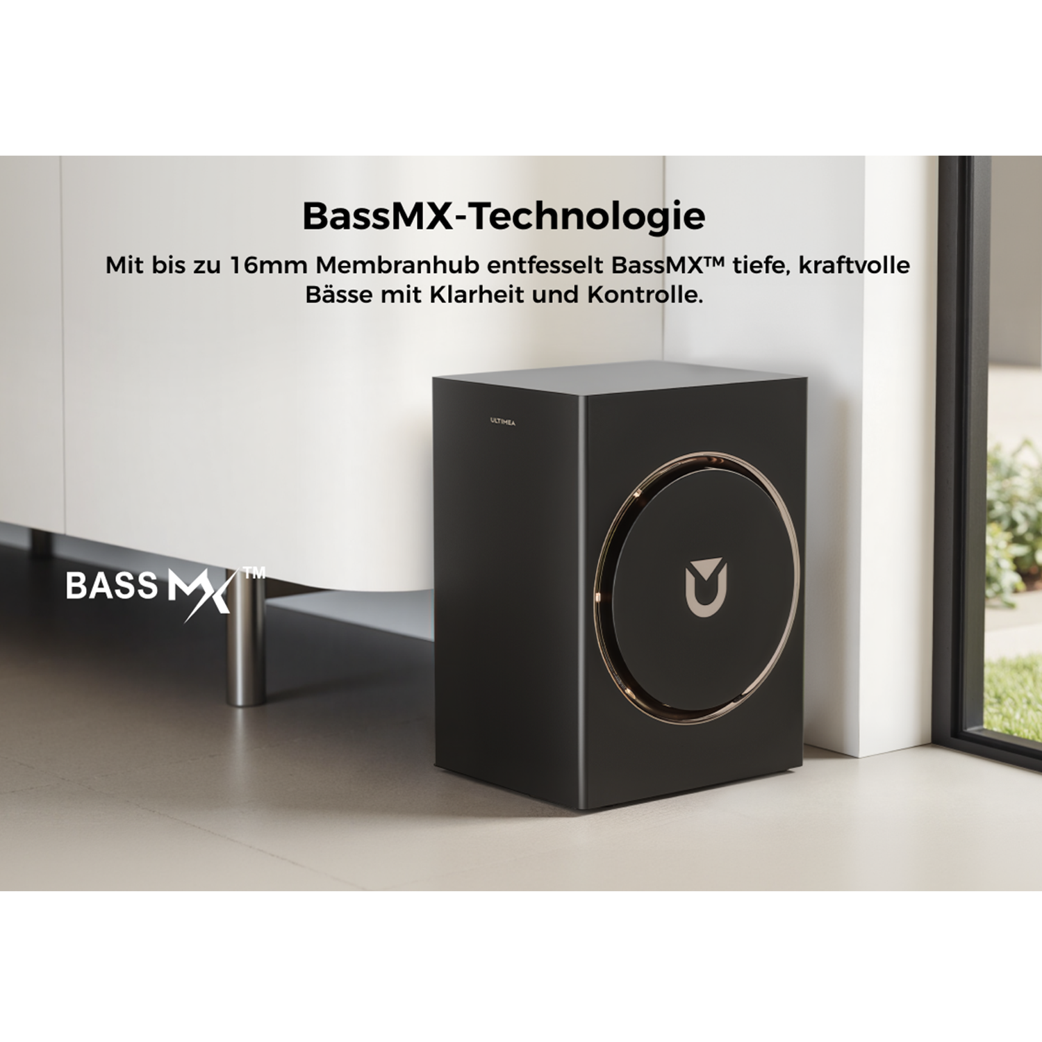 Schwarzer Subwoofer mit goldenem Ring und Logo. Er steht neben einem weißen Schrank und einem Fenster. Text: BassMX-Technologie.