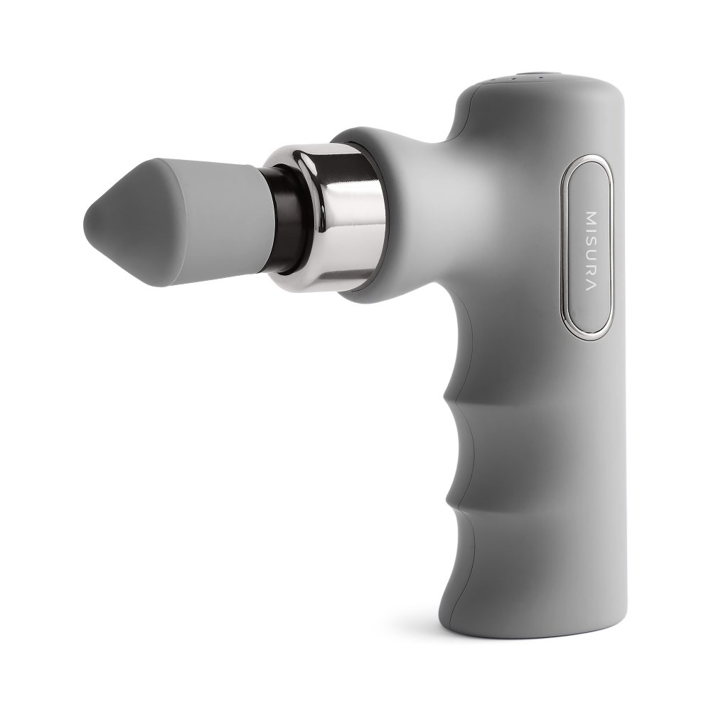 Szary pistolet do masażu na białym tle. Ma głowicę w kształcie stożka, srebrny pierścień i uchwyt z uchwytami. Widnieje na nim napis 'MISURA'.