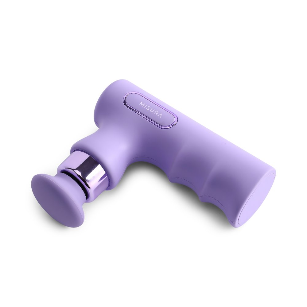 Fioletowy pistolet do masażu. Jest na nim napis 'MISURA'. Ma uchwyt i okrągłą głowicę. Tło jest białe.
