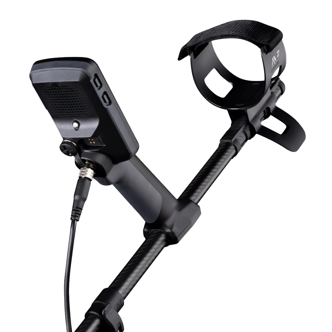 Un metal detector nero è visto in prospettiva. Ha un'impugnatura, un bracciolo e un pannello di controllo. Un cavo è collegato.