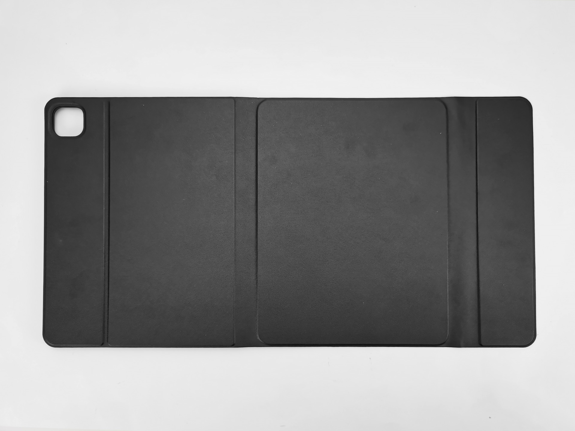 Eine schwarze Tablethülle ist auf einer weißen Oberfläche geöffnet. Die Hülle ist rechteckig mit abgerundeten Ecken und hat einen Kameraausschnitt.