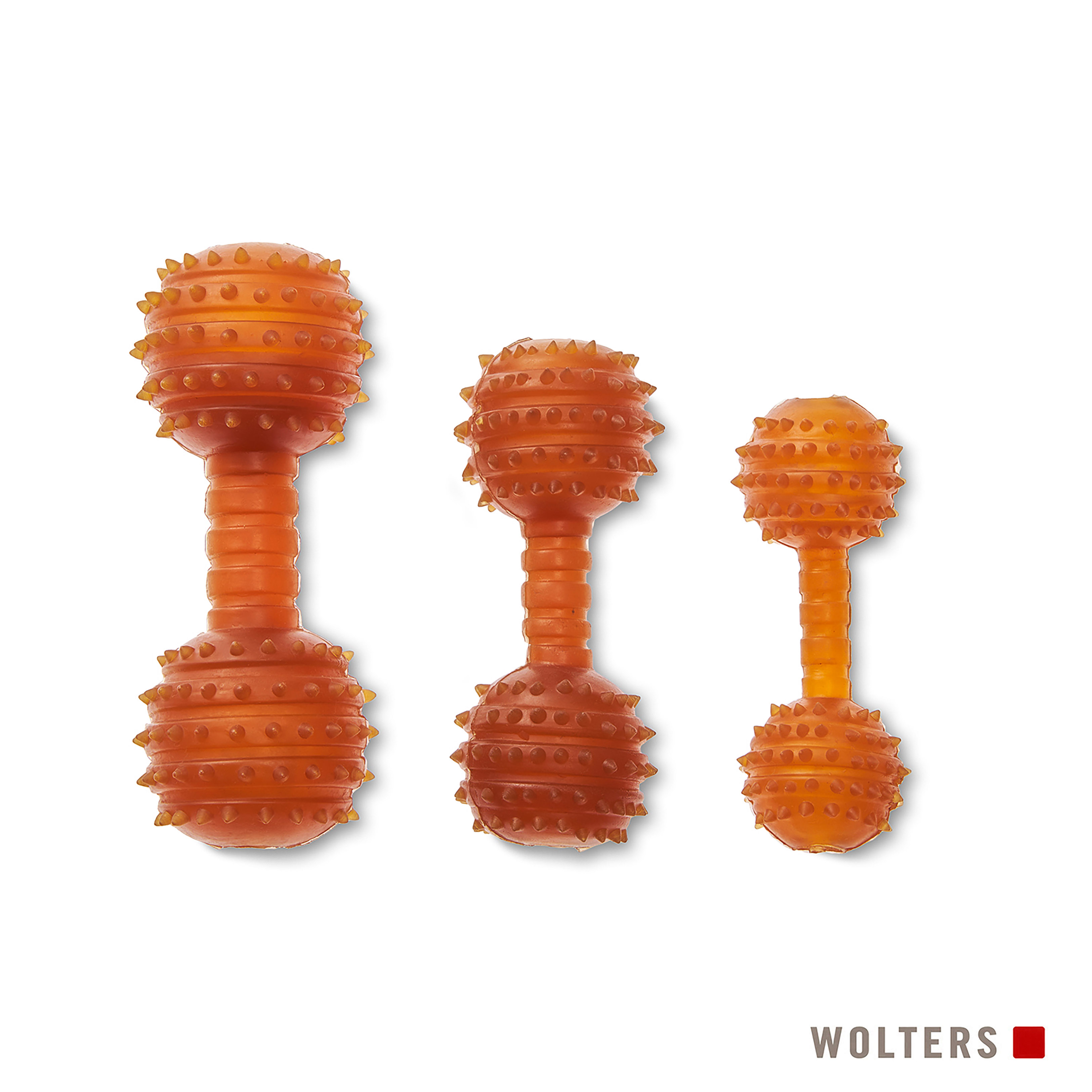 Drei orangefarbene Hundespielzeuge in Hantelform mit kleinen Stacheln an den abgerundeten Enden. Weißer Hintergrund, Wolters-Logo.