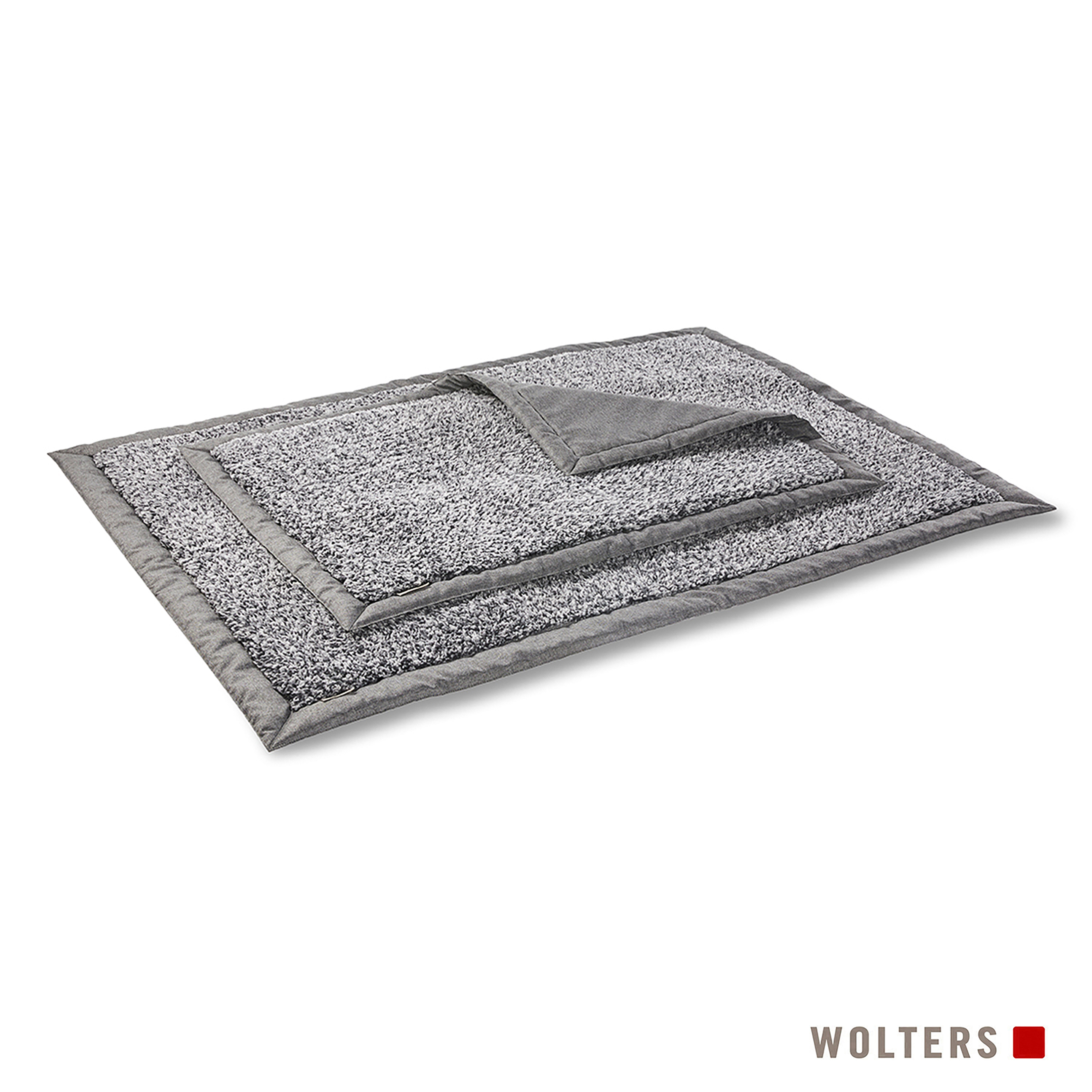 Ein graues Hundebett mit strukturierter Oberseite. Es hat einen dunkelgrauen Rand und einen kleineren, gefalteten Bereich.