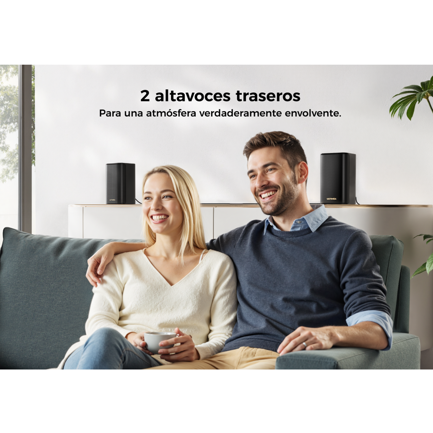 Una pareja sentada en un sofá. Dos altavoces negros detrás. El texto superior dice '2 altavoces traseros'.