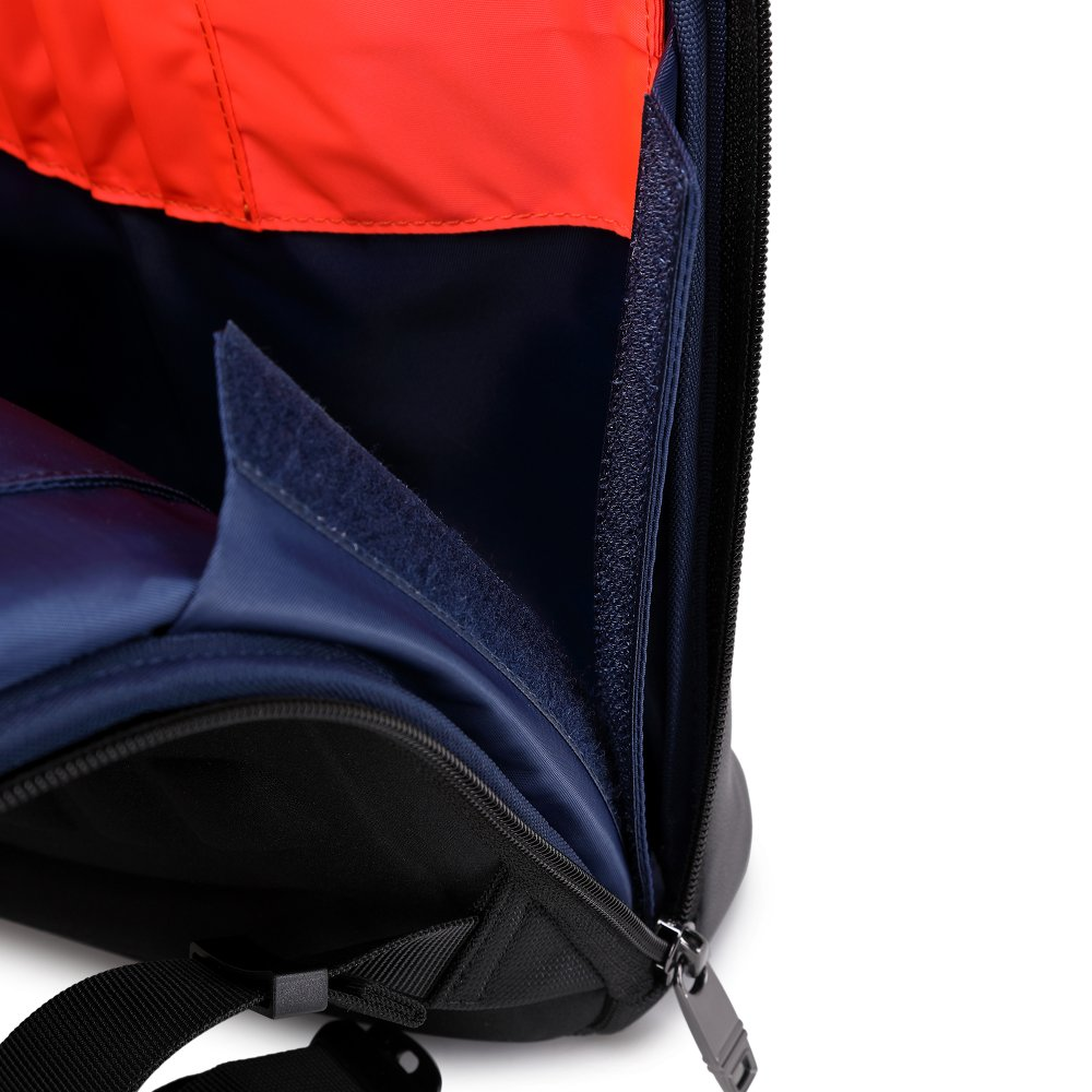 Zaino nero aperto con interno arancione e blu. La cerniera è parzialmente aperta. Velcro e cinghie visibili.