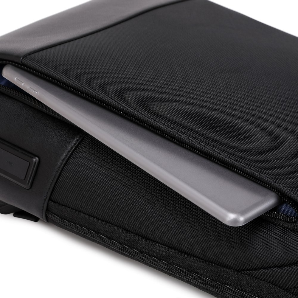 Una borsa nera con un tablet grigio parzialmente all'interno. La borsa ha una cerniera e un piccolo bottone nero. Lo sfondo è bianco.