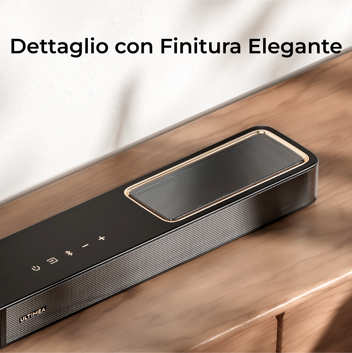 Una soundbar nera con griglia a rete su una superficie in legno. Ha pulsanti di controllo e il marchio stampato.
