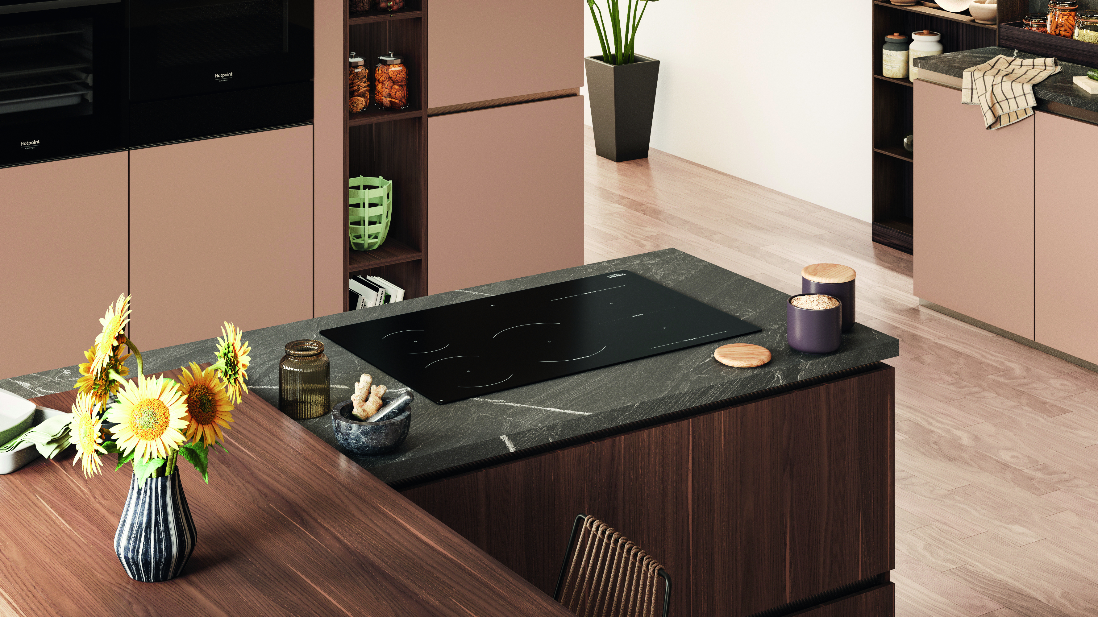 Un interno cucina con un vaso di fiori su un tavolo di legno. Sono visibili anche un piano cottura nero e un mobile in legno.