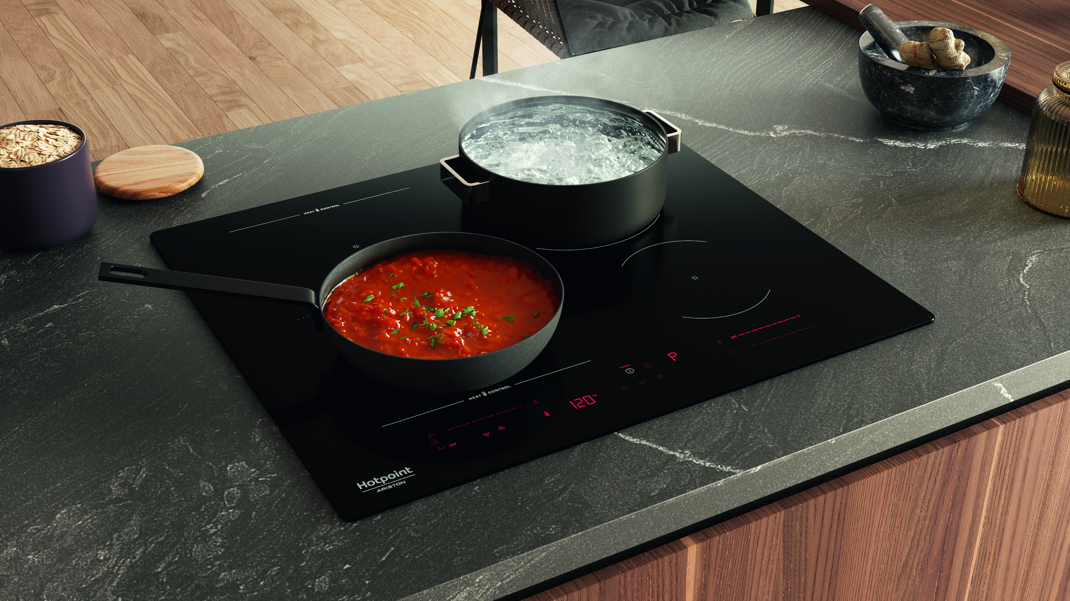 Una scena di cucina con piano cottura nero. Pentole con acqua bollente e salsa di pomodoro. Avena, mortaio e superficie in legno.