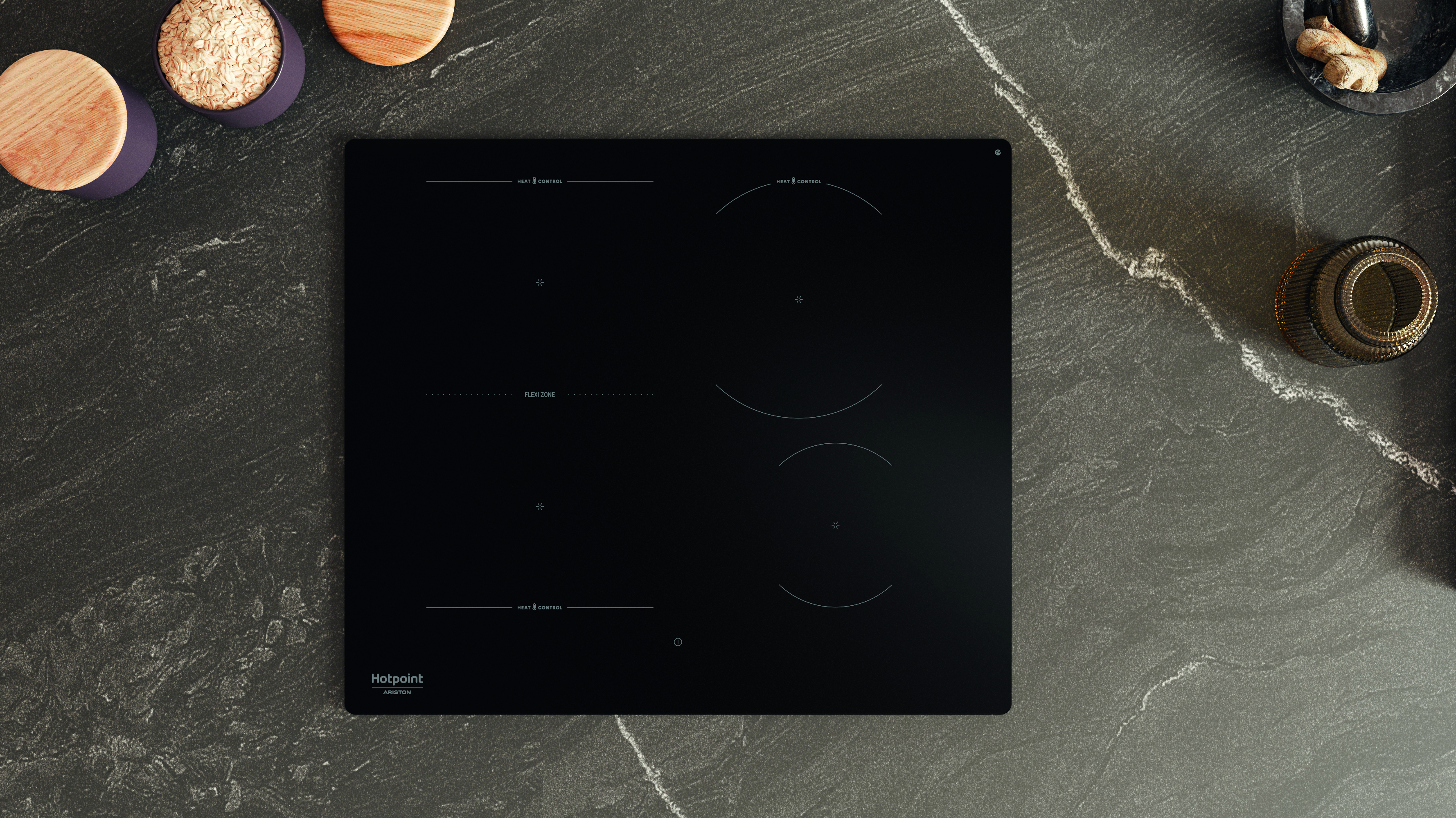 Un piano cottura a induzione nero con zone cottura. Ciotole con ingredienti e un barattolo sul piano scuro.