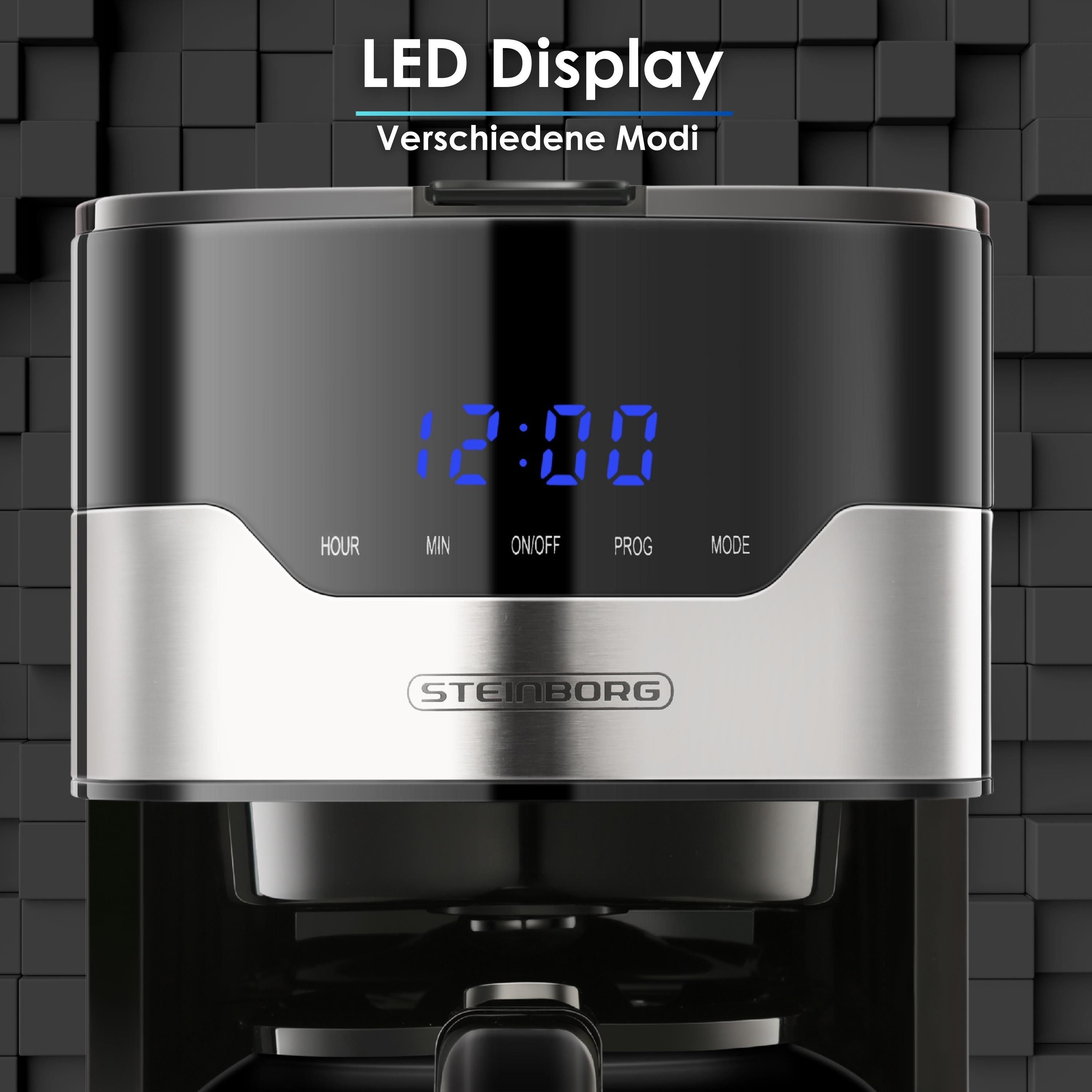 Nahaufnahme eines schwarzen Kaffeeautomaten mit digitaler Anzeige 12:00. Die Marke ist Steinborg. Hintergrund sind schwarze Würfel.