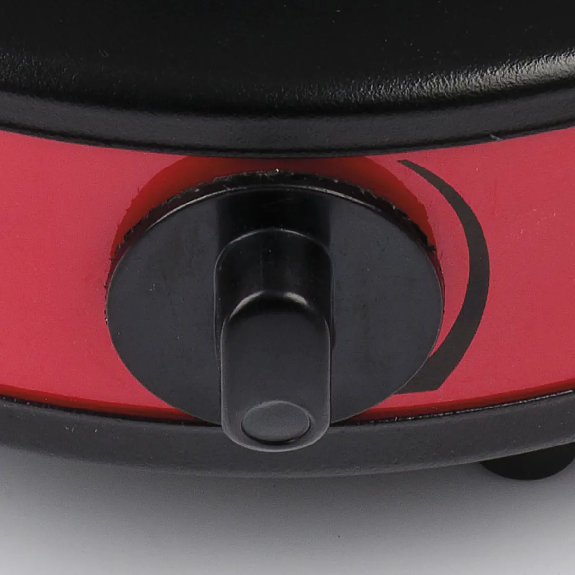 Zbliżenie czerwono-czarnego urządzenia z czarnym pokrętłem. Pokrętło jest na środku, z zakrzywionym czarnym wzorem na czerwonej powierzchni.