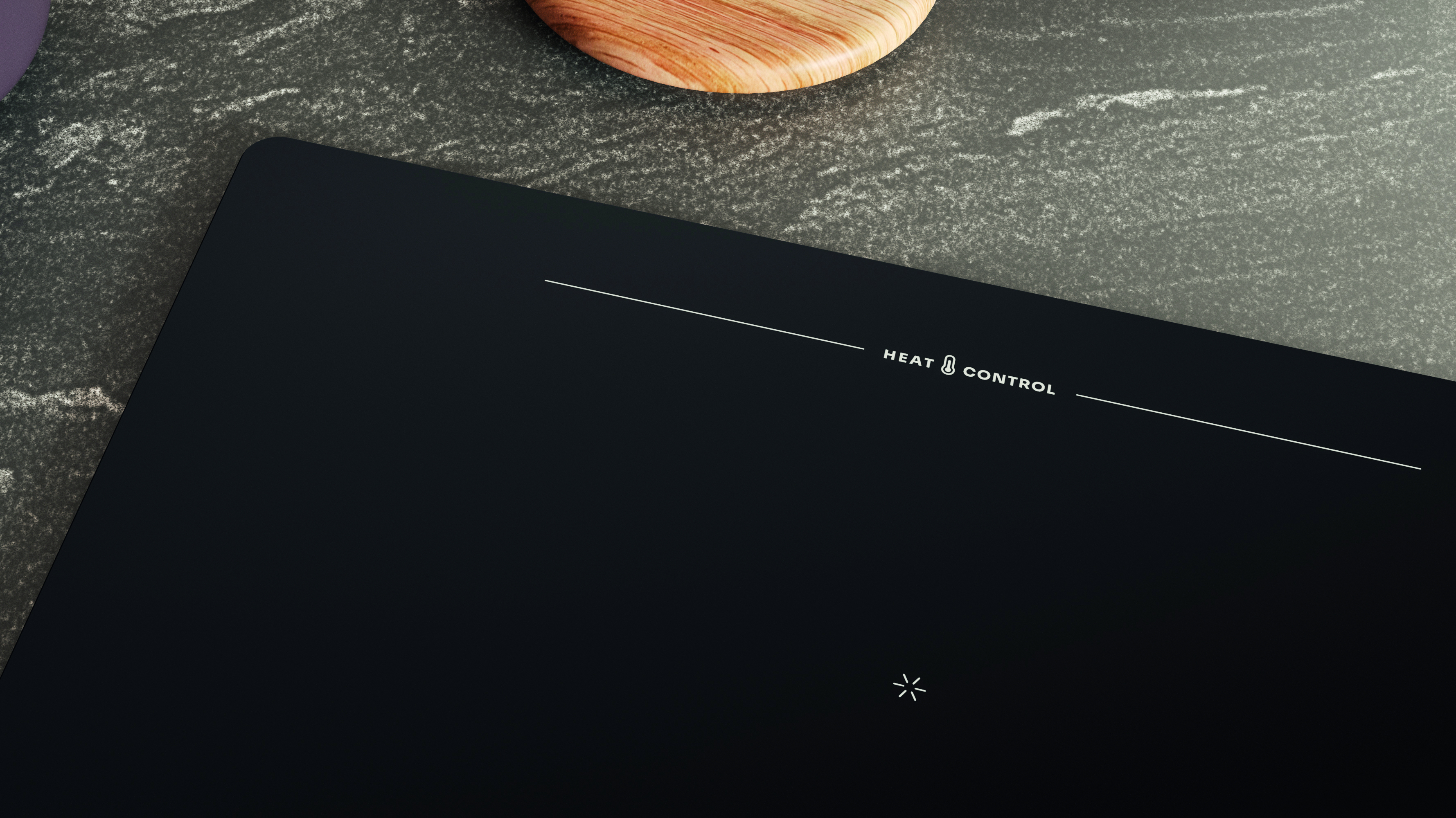 Piano cottura a induzione nero con segni bianchi e testo 'HEAT CONTROL'. Un tagliere in legno sullo sfondo su una superficie grigia.