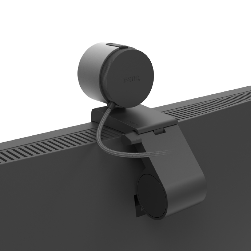 Czarna kamera internetowa jest zamontowana na czarnym monitorze. Kamera internetowa ma cylindryczną konstrukcję. Widoczne jest logo BenQ.