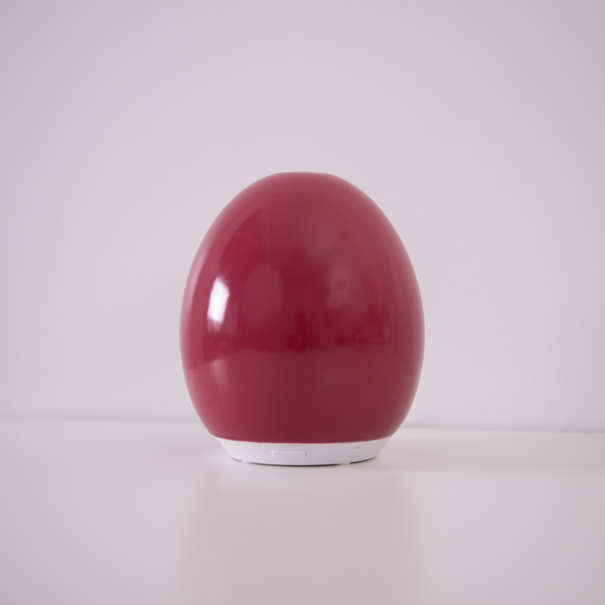 A red, spherical diffuser sits on a white surface. The background is white.