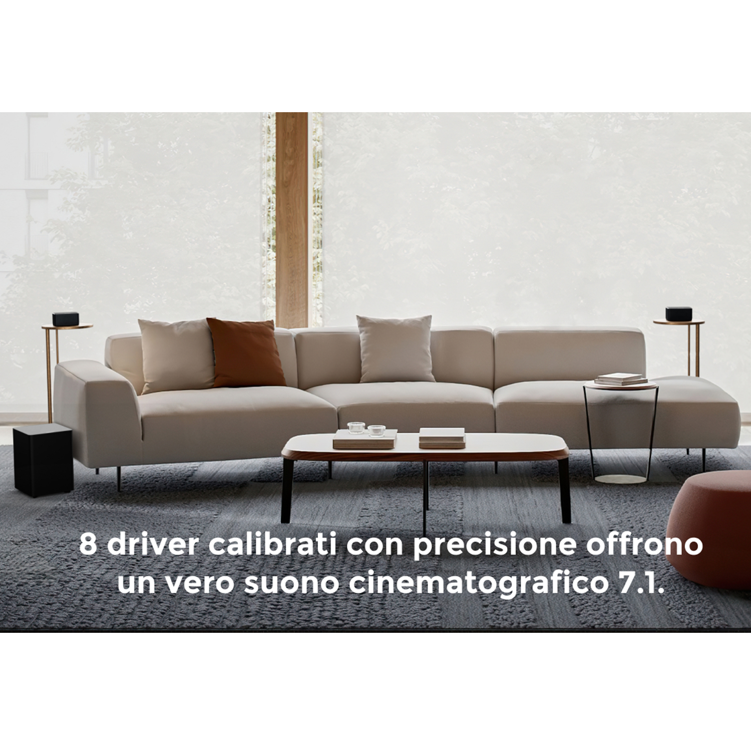 Soggiorno moderno con divano beige, tavolino, altoparlanti e grande finestra. Testo in italiano.