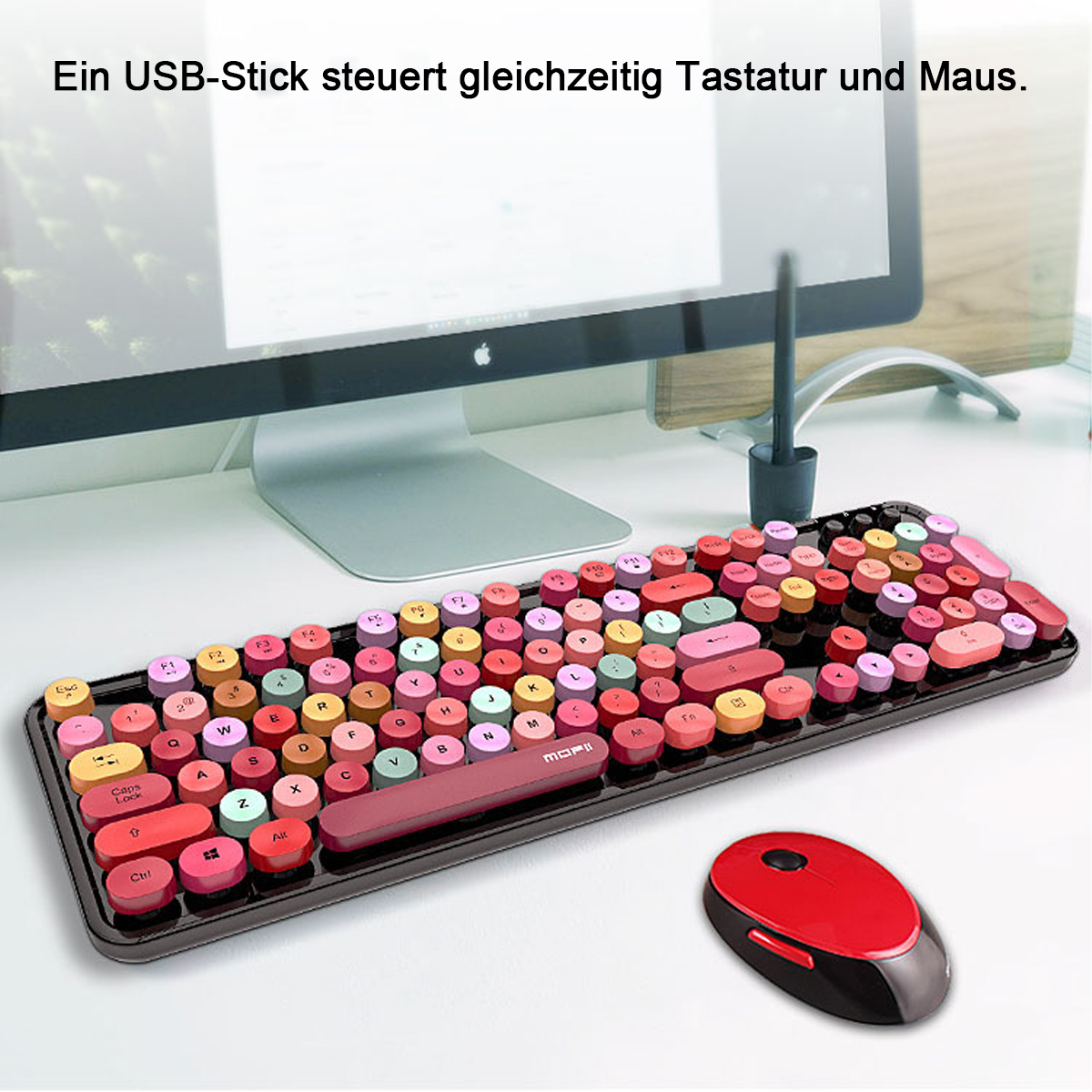 Un teclado colorido y un ratón rojo están sobre un escritorio blanco. Un monitor y un lápiz óptico son visibles en el fondo.