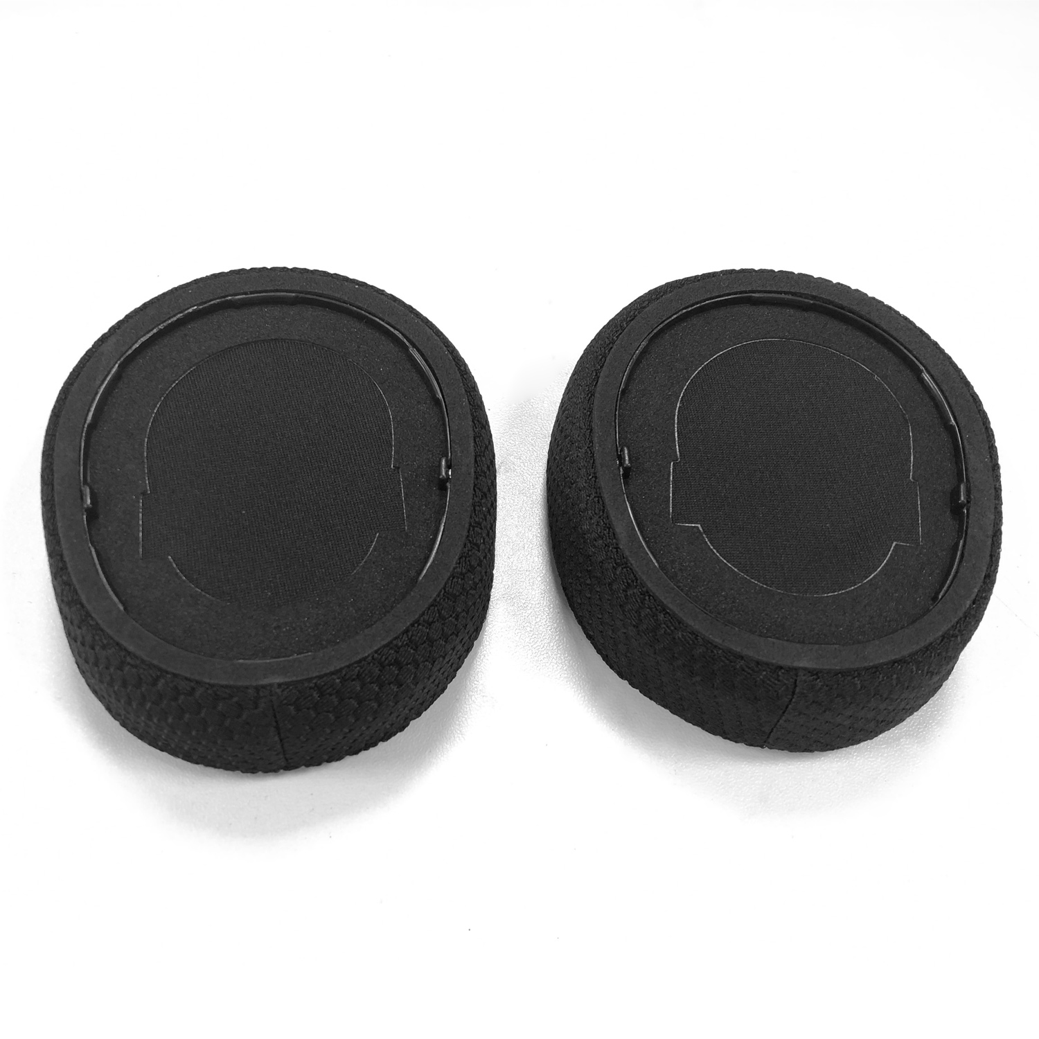 Dwie czarne poduszki nauszne do słuchawek na białej powierzchni. Każda ma centralny okrąg z materiału i teksturowany pierścień zewnętrzny.