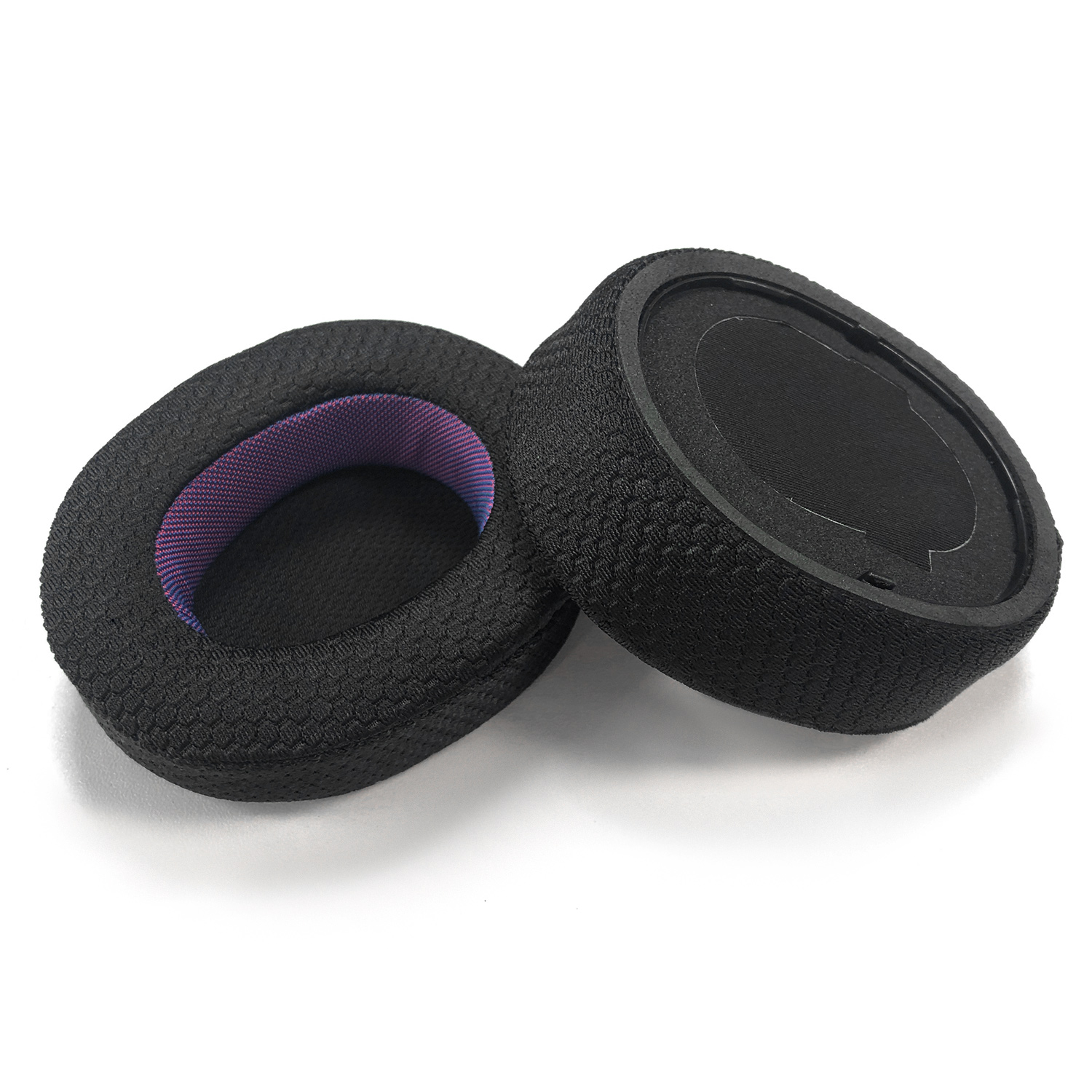 Dwie czarne nausznice do słuchawek na białej powierzchni. Jedna stoi pionowo, druga jest pochylona, ​​pokazując fioletowo-różową siatkę.