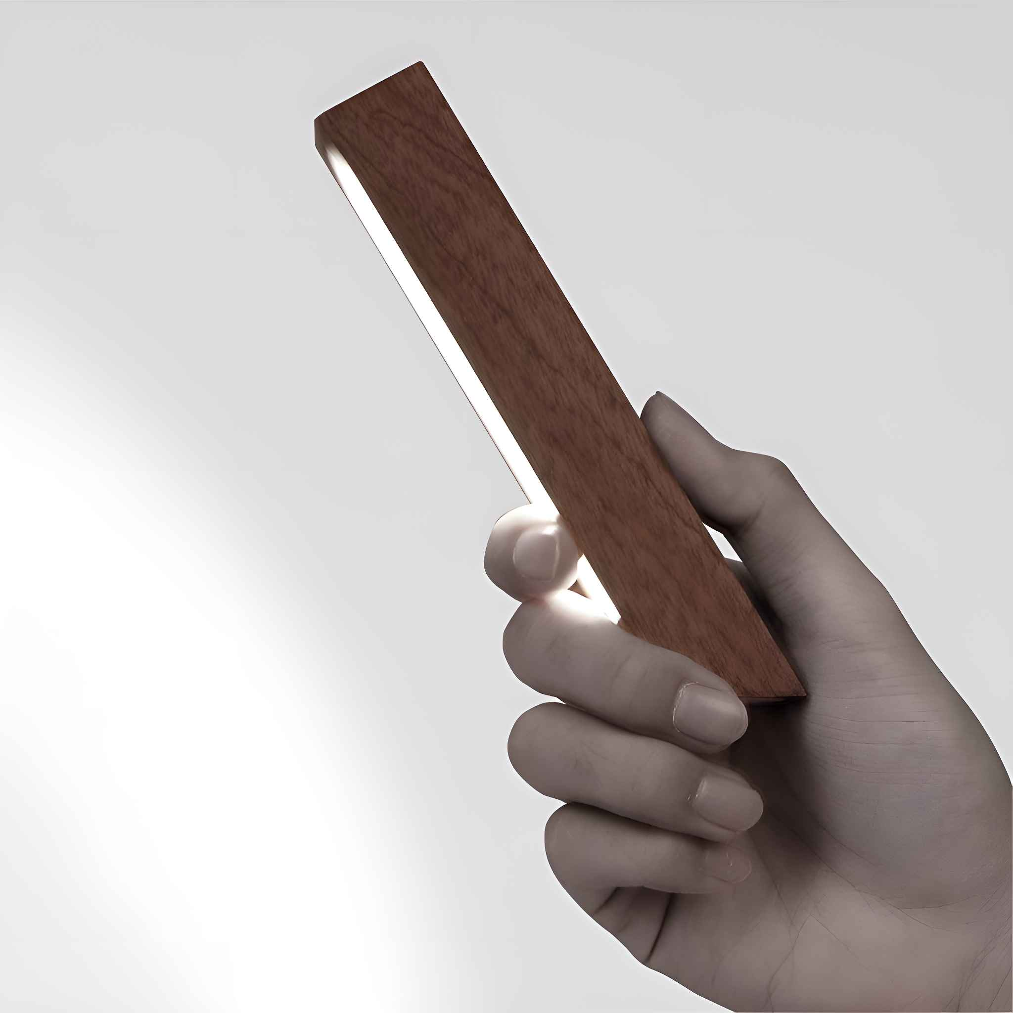 Eine Hand hält ein rechteckiges Holzlicht. Das Licht scheint aus einer schmalen Öffnung. Der Hintergrund ist weiß.