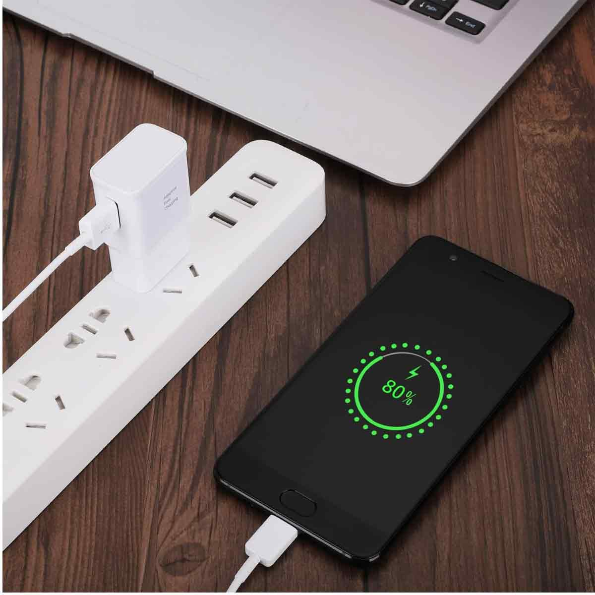 Ein schwarzes Telefon, das geladen wird und 80 % Akku anzeigt. Eine weiße Steckdosenleiste und ein Ladegerät sind ebenfalls zu sehen, zusammen mit einem Laptop.