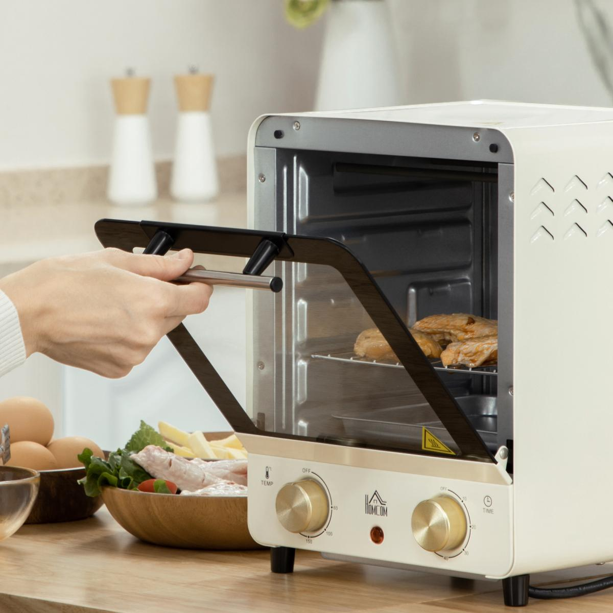Eine Person öffnet eine Backofentür. Im Inneren befindet sich gekochtes Essen auf einem Rost. Zutaten, Eier und eine Holzschüssel mit Essen sind in der Nähe.