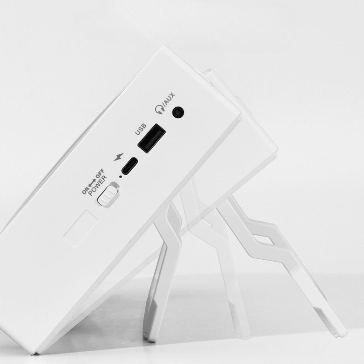 Ein weißes elektronisches Gerät, möglicherweise ein Lautsprecher, ist gekippt. Es hat USB-, AUX-Anschlüsse und einen Ein-/Ausschalter. Von weißen Beinen getragen.