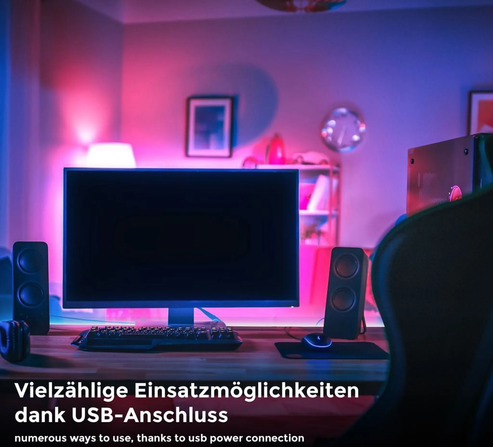 Gaming-Setup mit Monitor, Lautsprechern, Tastatur und Maus. Der Raum ist rosa und blau beleuchtet.