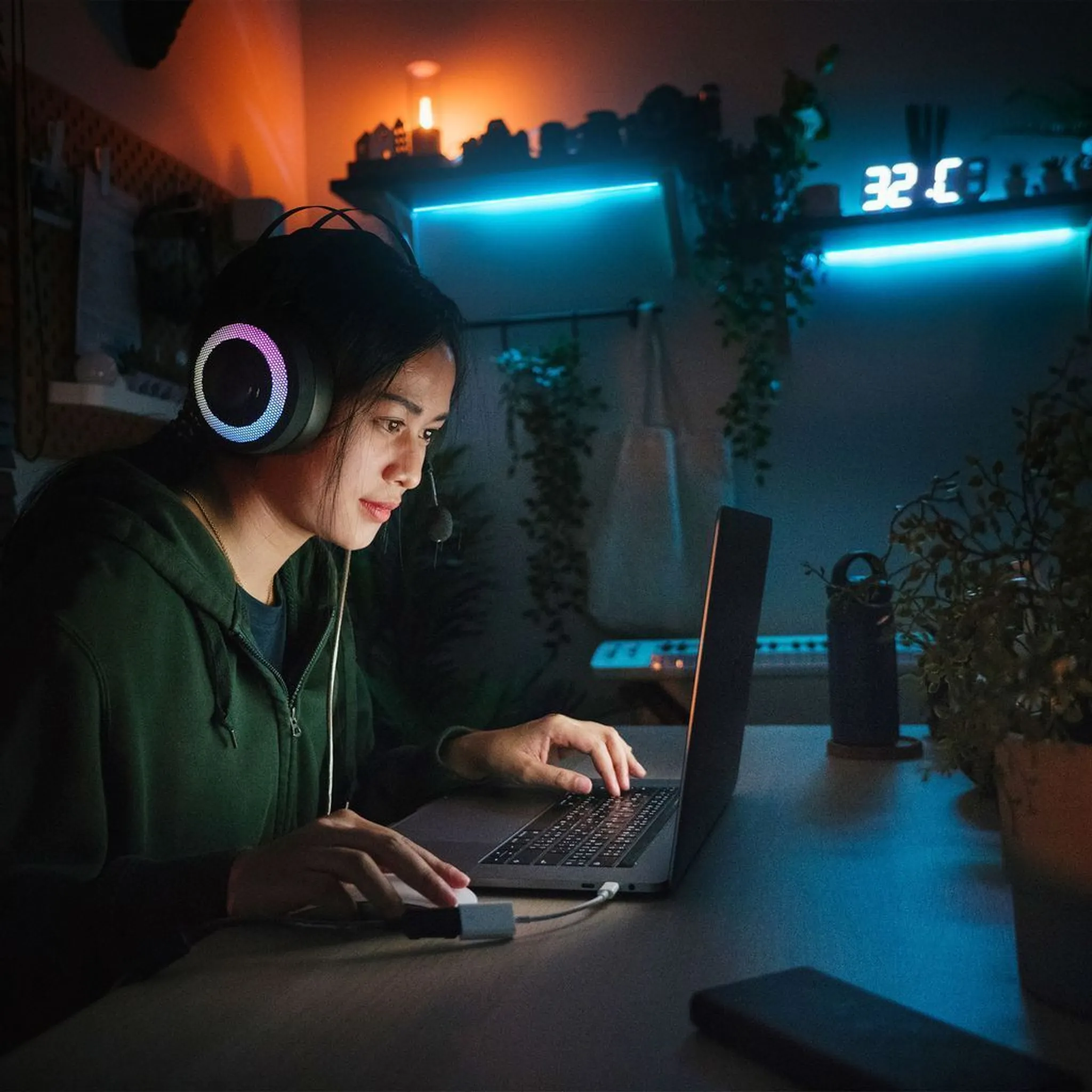 Eine Person mit Headset und Laptop. Der Raum ist schwach beleuchtet mit Neonlicht. Die Person konzentriert sich auf den Bildschirm.
