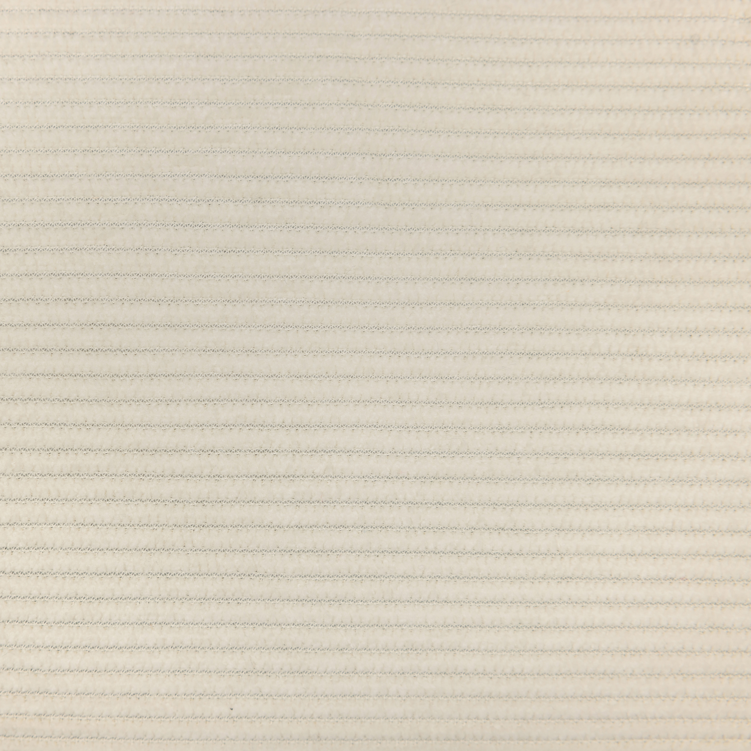 Nahaufnahme eines strukturierten Stoffes. Horizontale Linien bilden sich durch sich wiederholende Muster. Die Farbe ist hellbeige.