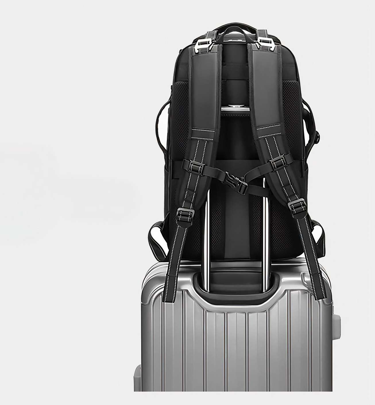 Ein schwarzer Rucksack liegt auf einem silbernen Koffer. Beide haben weiße Akzente. Die Szene spielt vor einem weißen Hintergrund.
