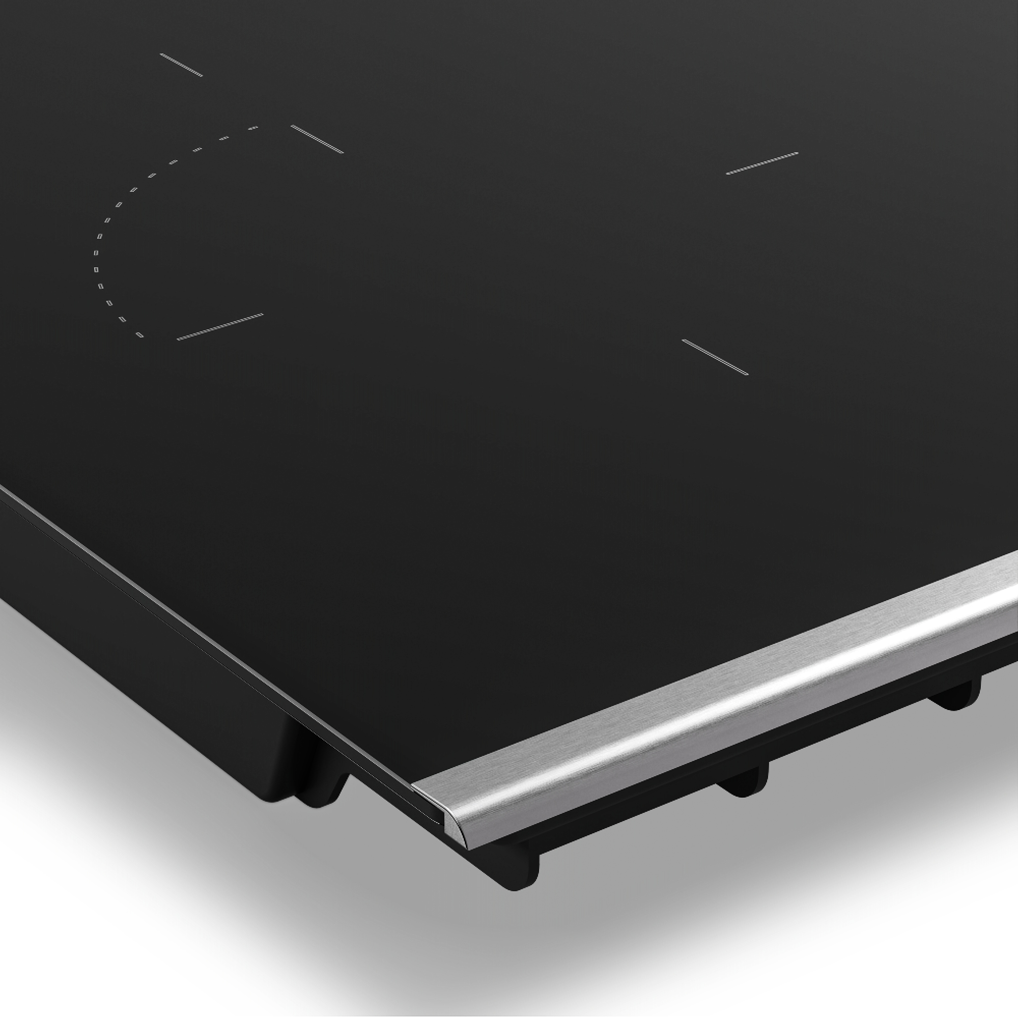 Primer plano de una placa de cocina de vidrio negro con borde plateado. Tiene zonas de calentamiento marcadas. Fondo blanco.