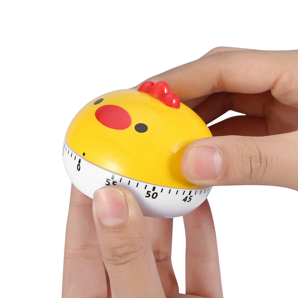 Ein gelber, huhnförmiger Timer wird von Händen gehalten. Er hat einen roten Kamm, schwarze Augen und eine weiße Basis mit Zahlen.