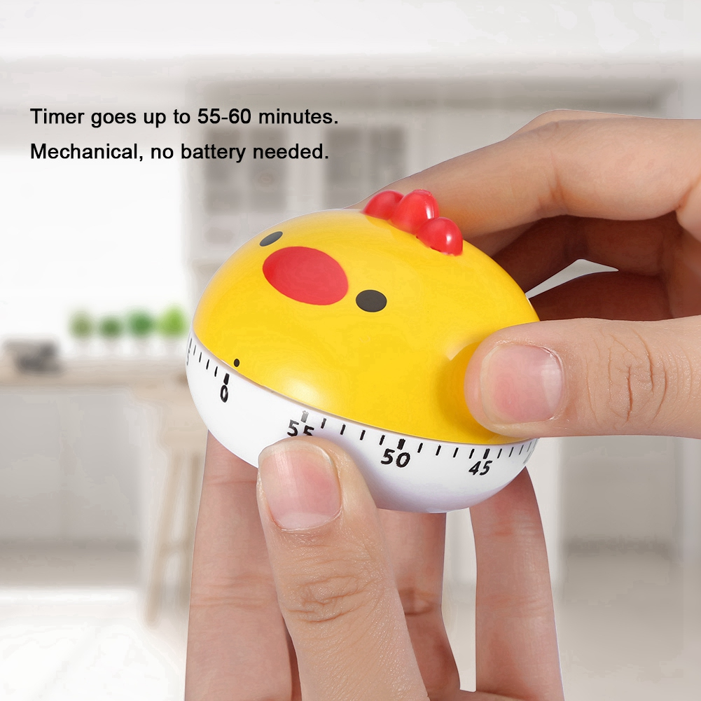 Ein gelber, huhnförmiger Küchentimer wird von einer Person gehalten. Der Timer zeigt Zahlen und einen roten Kamm. Er ist mechanisch, keine Batterie.