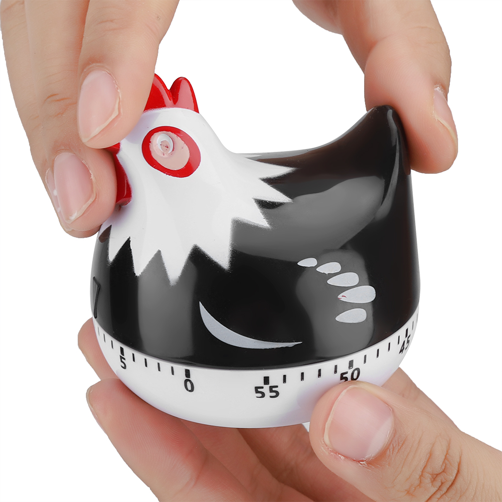 Ein schwarz-weißer, hühnerförmiger Küchentimer wird von zwei Händen gehalten. Der Timer hat einen roten Kamm und ein weißes Gesicht mit schwarzem Körper.